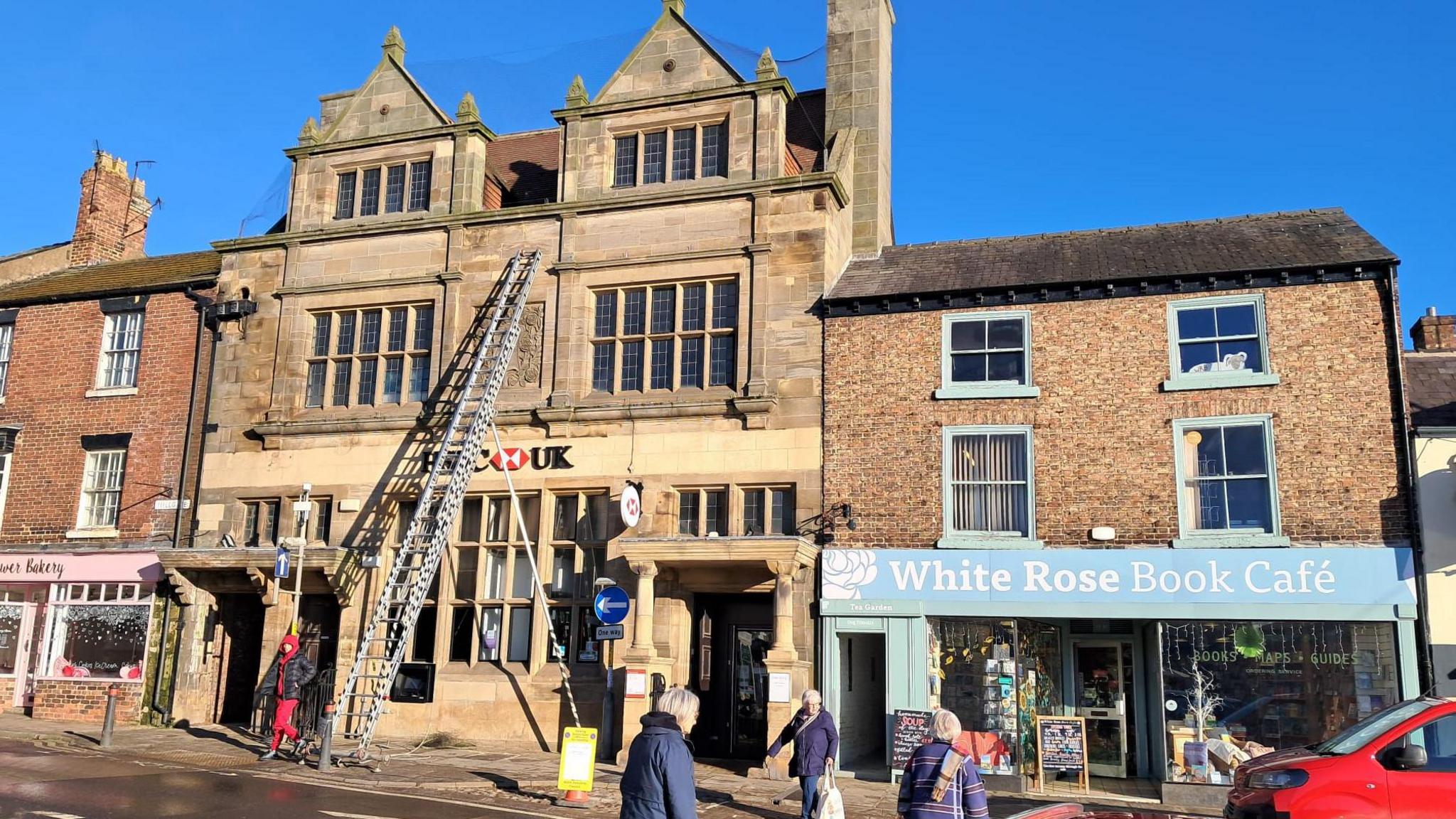 Firefighters attempt to rescue trapped bird on the roof of HSBC while passers-by look on