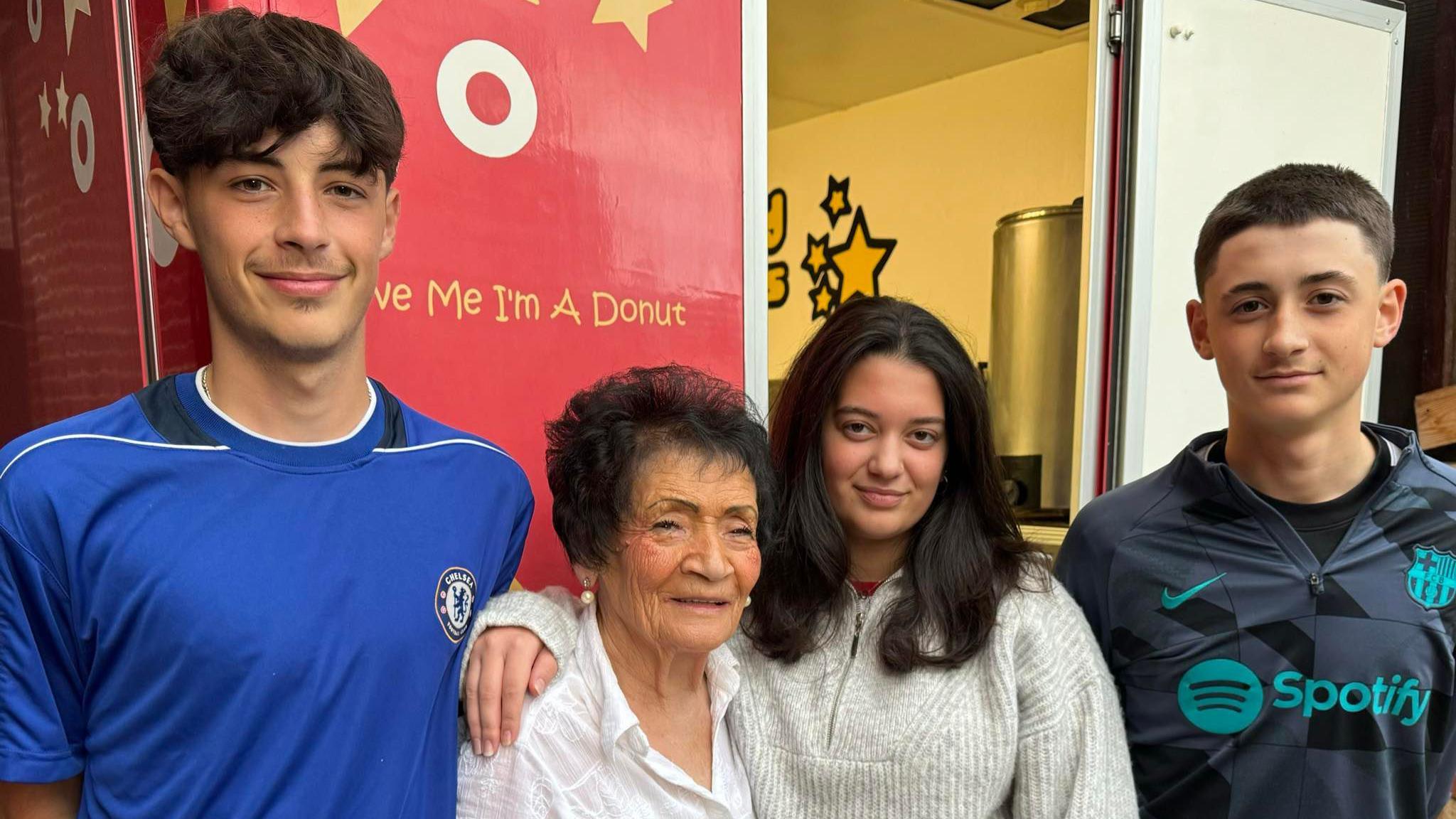 Lina with three of her grandchildren standing by her food stand.