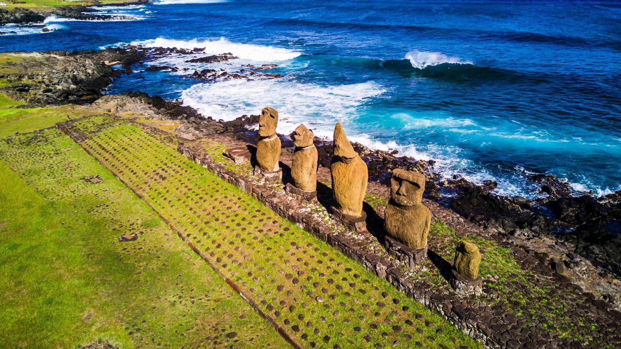 Moais standing facing the elements on the coast of Easter Island with the sea in the background
