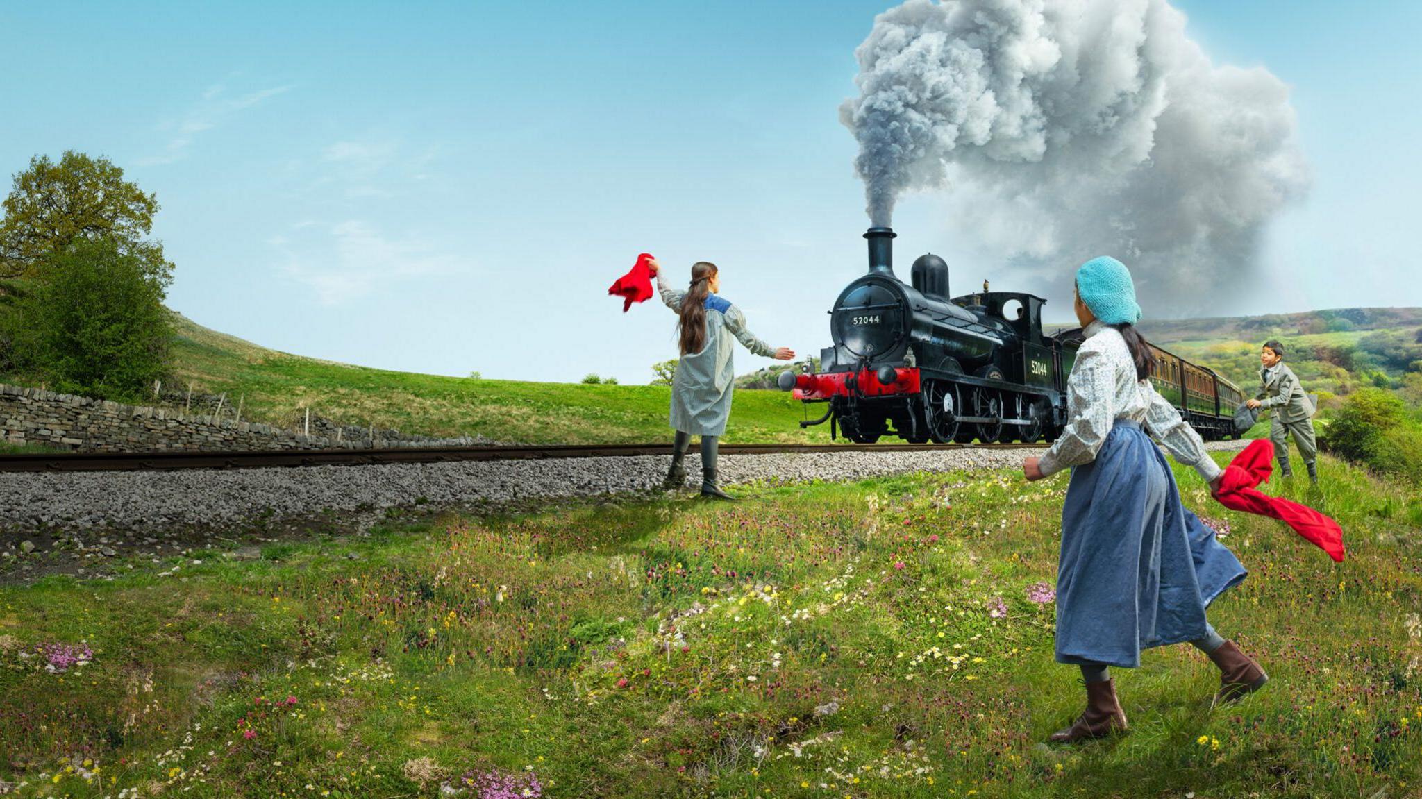 Three children playing on grass with a steam train going by