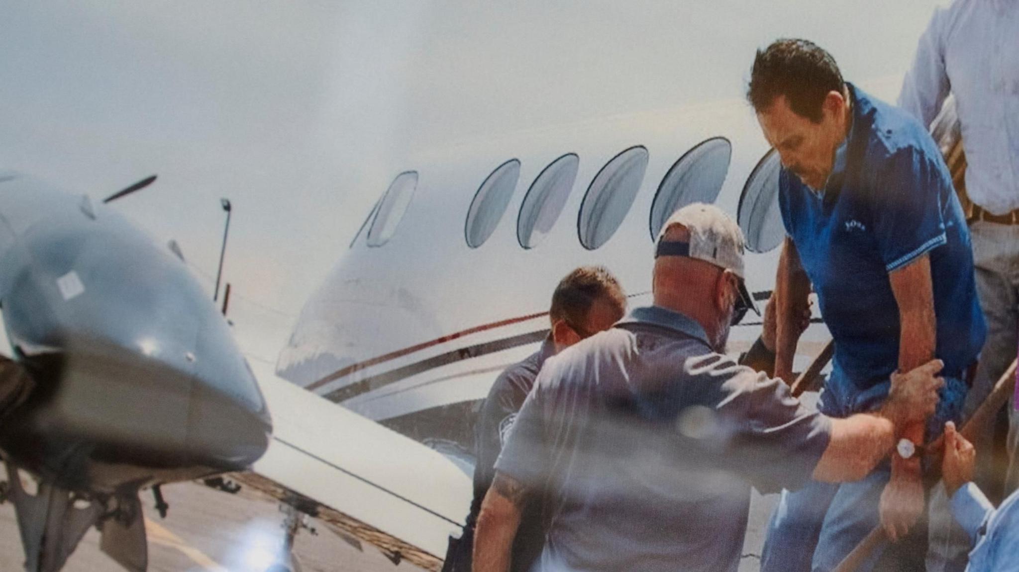 Zambada, in a blue golf shirt, is helped off a small plane while being taken into custody in July 2024