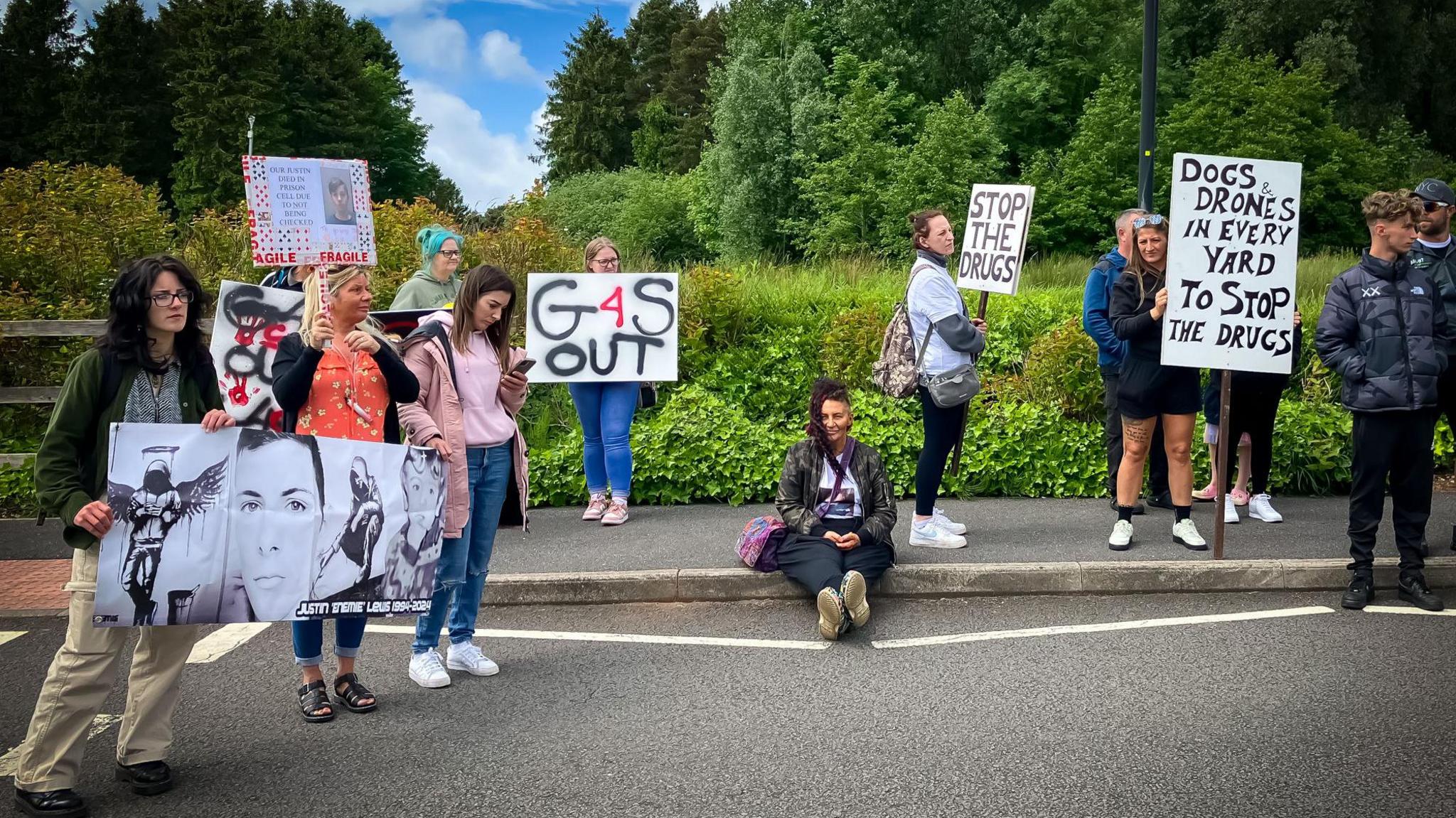 A group of protestor on a roadside with signs saying things like G4S out and stop the drugs