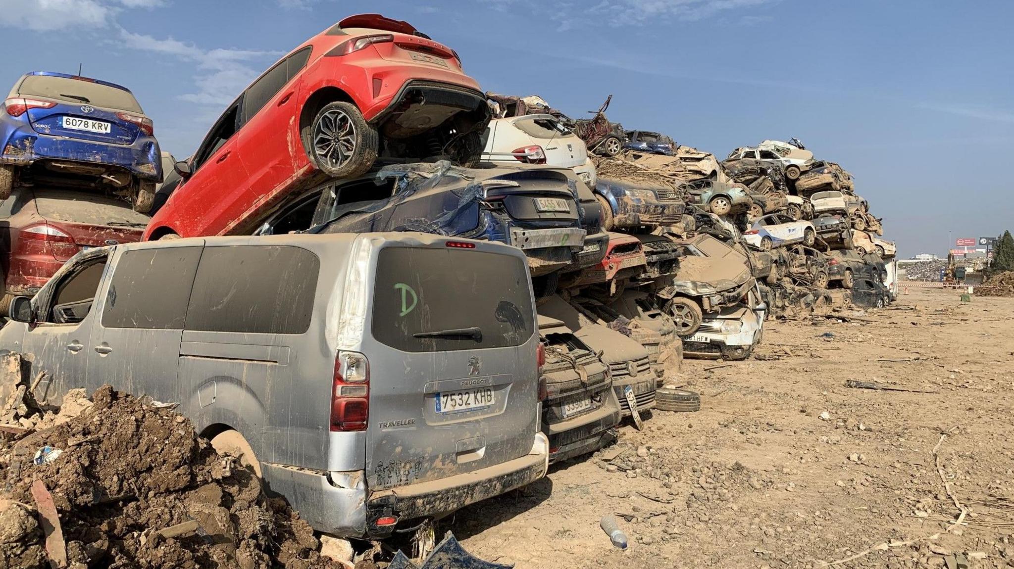 Vehicles that were damaged in the floods piled on top of each other