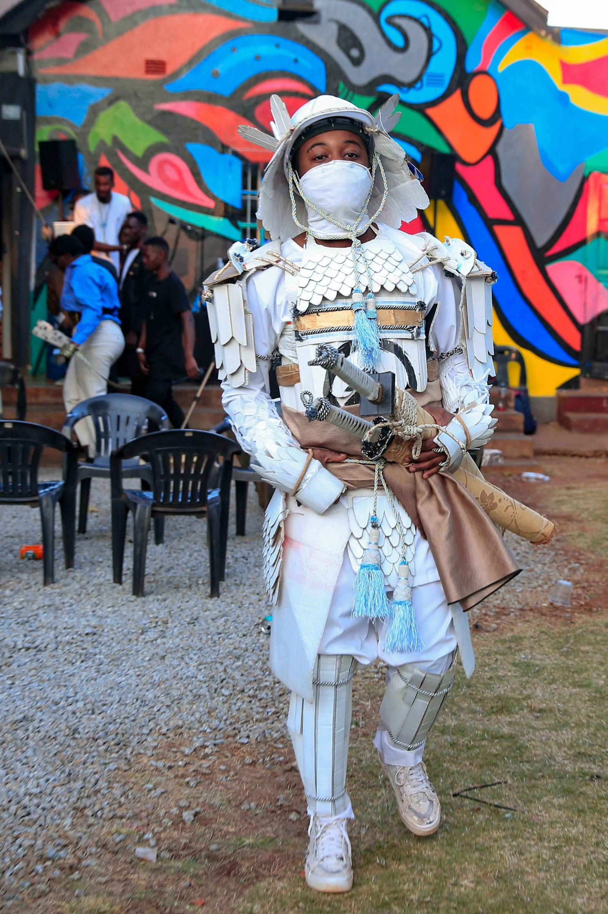 Cosplay player Gabriel Ota walks during an anime, manga and cosplay meeting. He is dressed as popular Japanese action game character, Jin Sakai, the sword-wielding protagonist of Ghost of Tsushima. He is wearing a white samurai outfit made of cardboard and recycled paper.