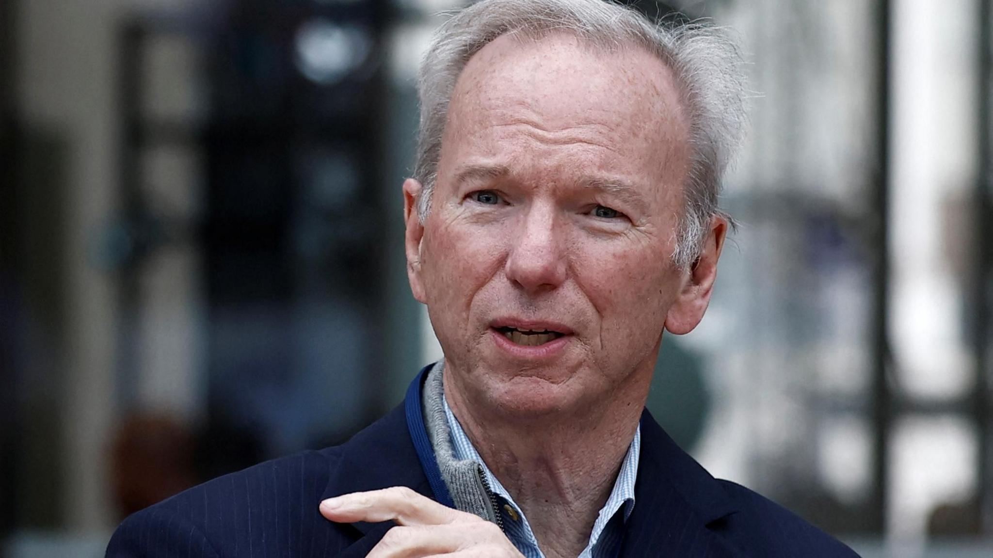 Eric Schmidt wearing a dark jacket and pinstriped shirt, gesticulating with his hand as he speaks.