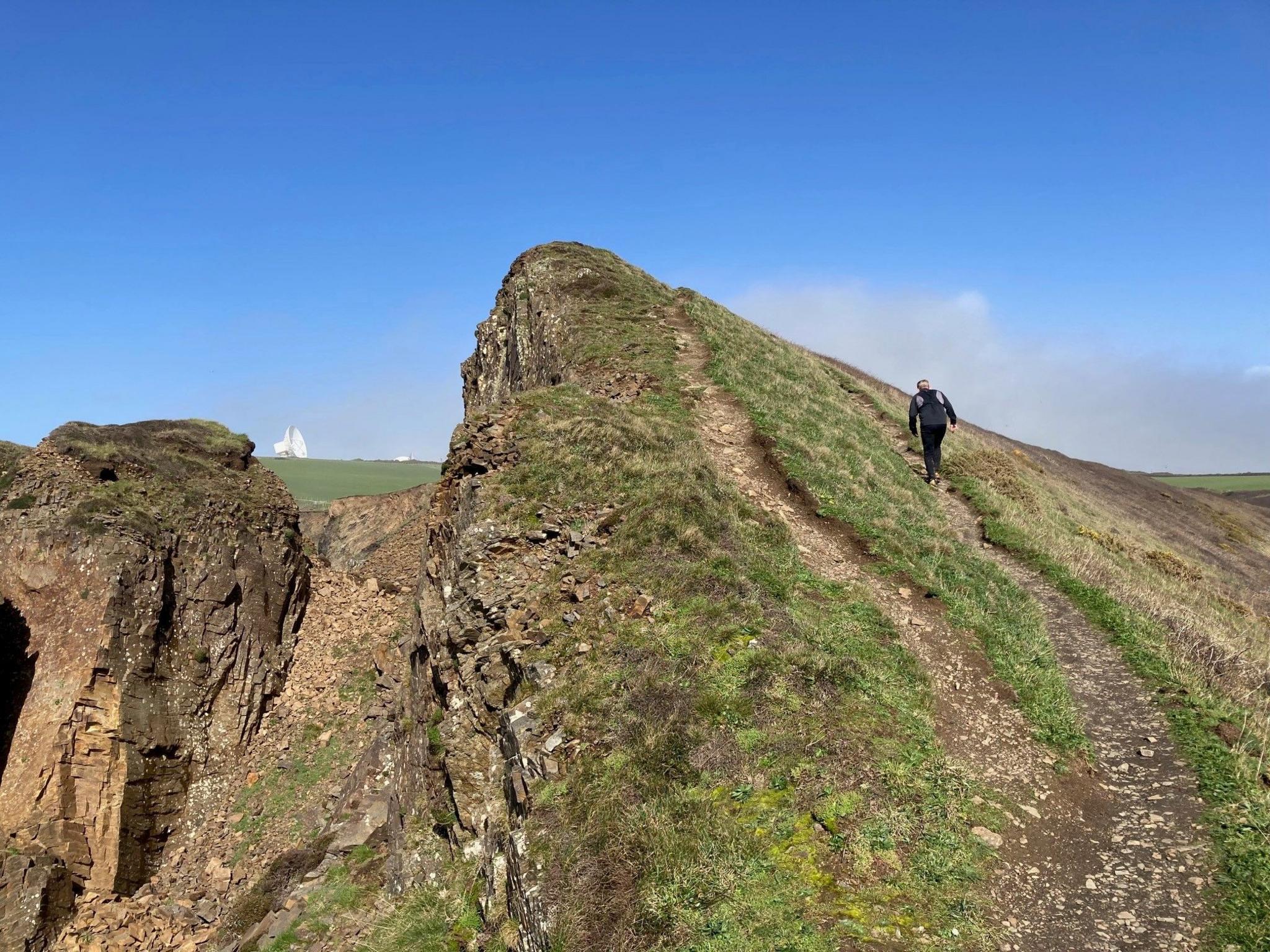 A man runs up a steep coast path in Cornwall