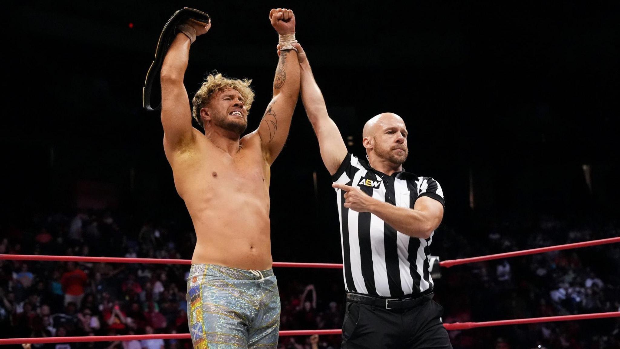 Will Ospreay's arms are held aloft by a referee after winning a bout