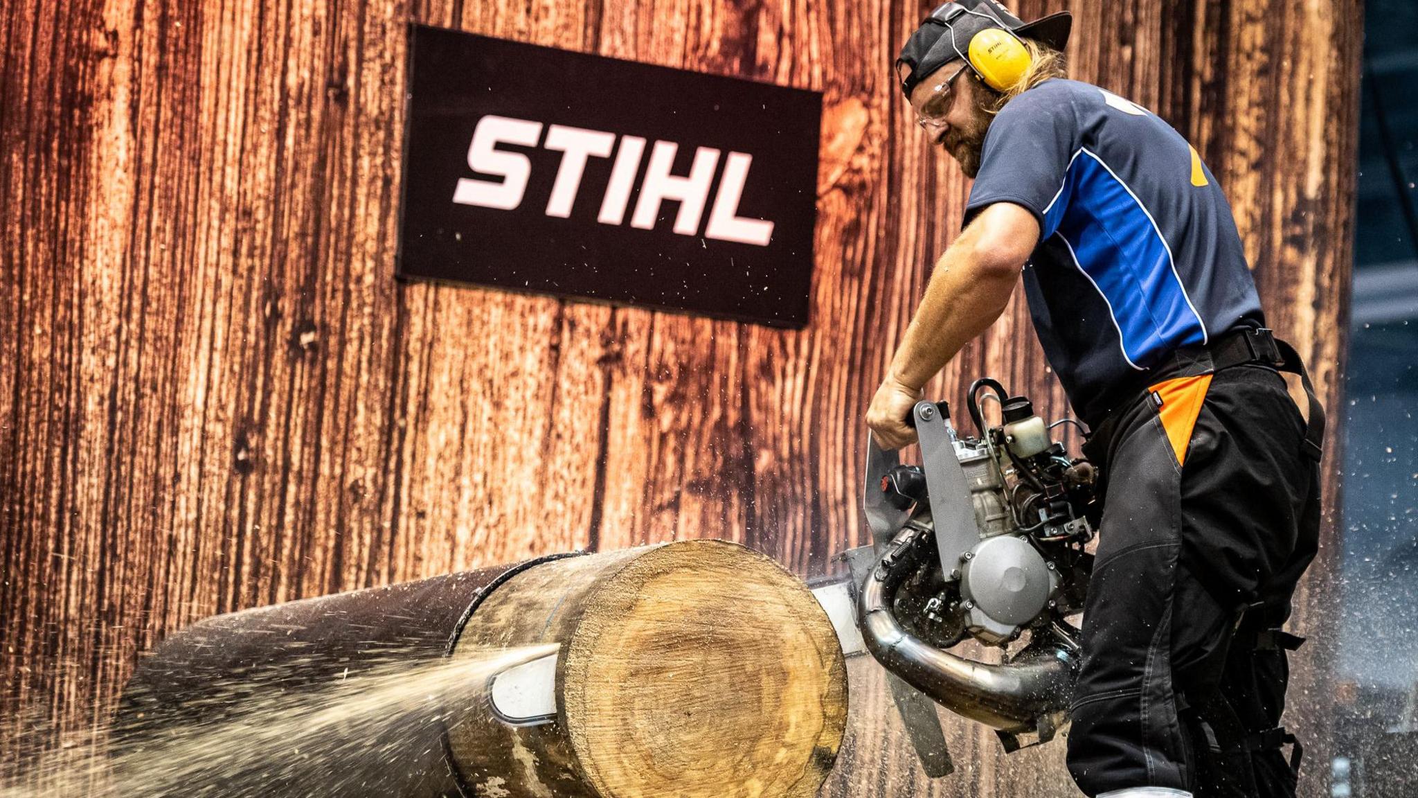 A man using a chainsaw on a log in the contest.