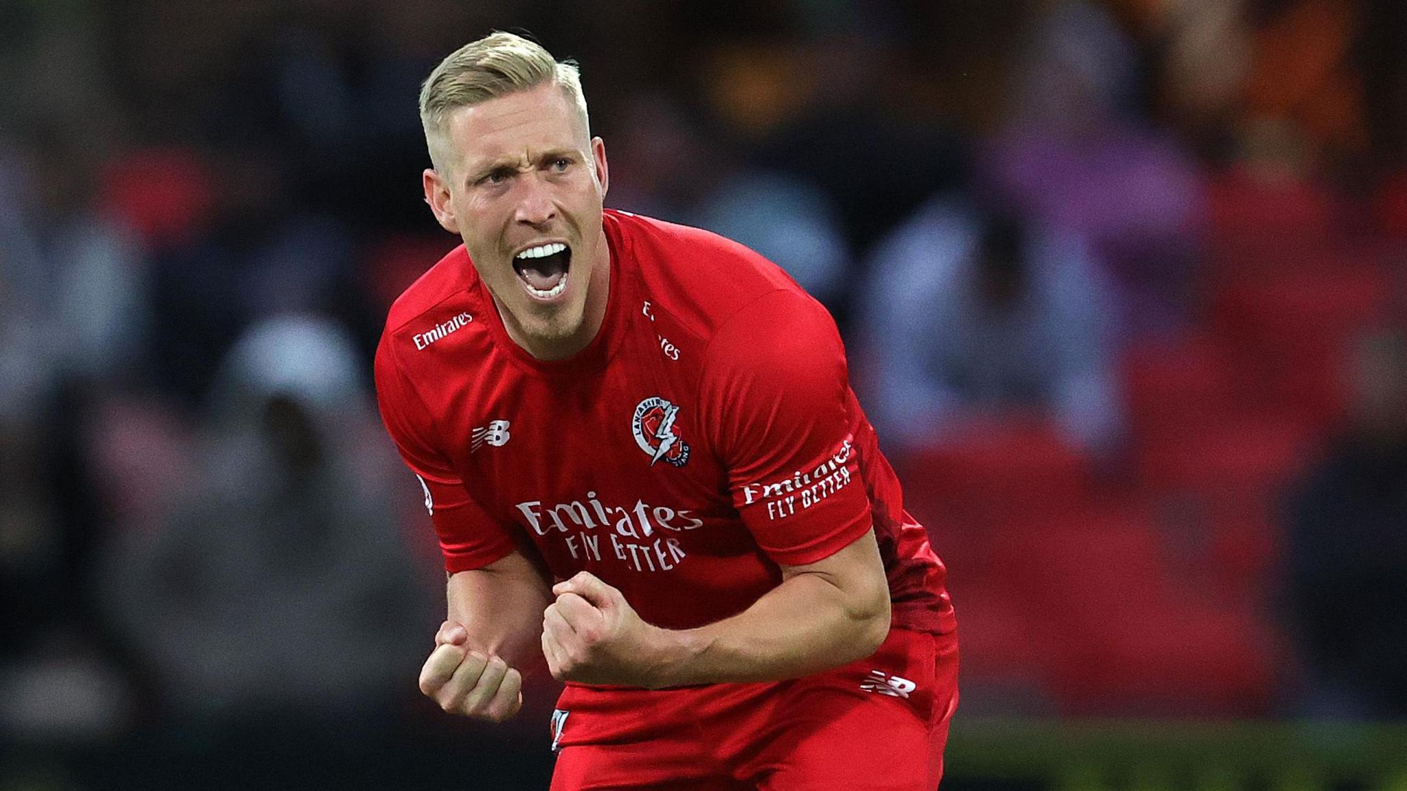 Luke Wood, slightly crouched, with his fists clenched, after taking a wicket for Lancashire