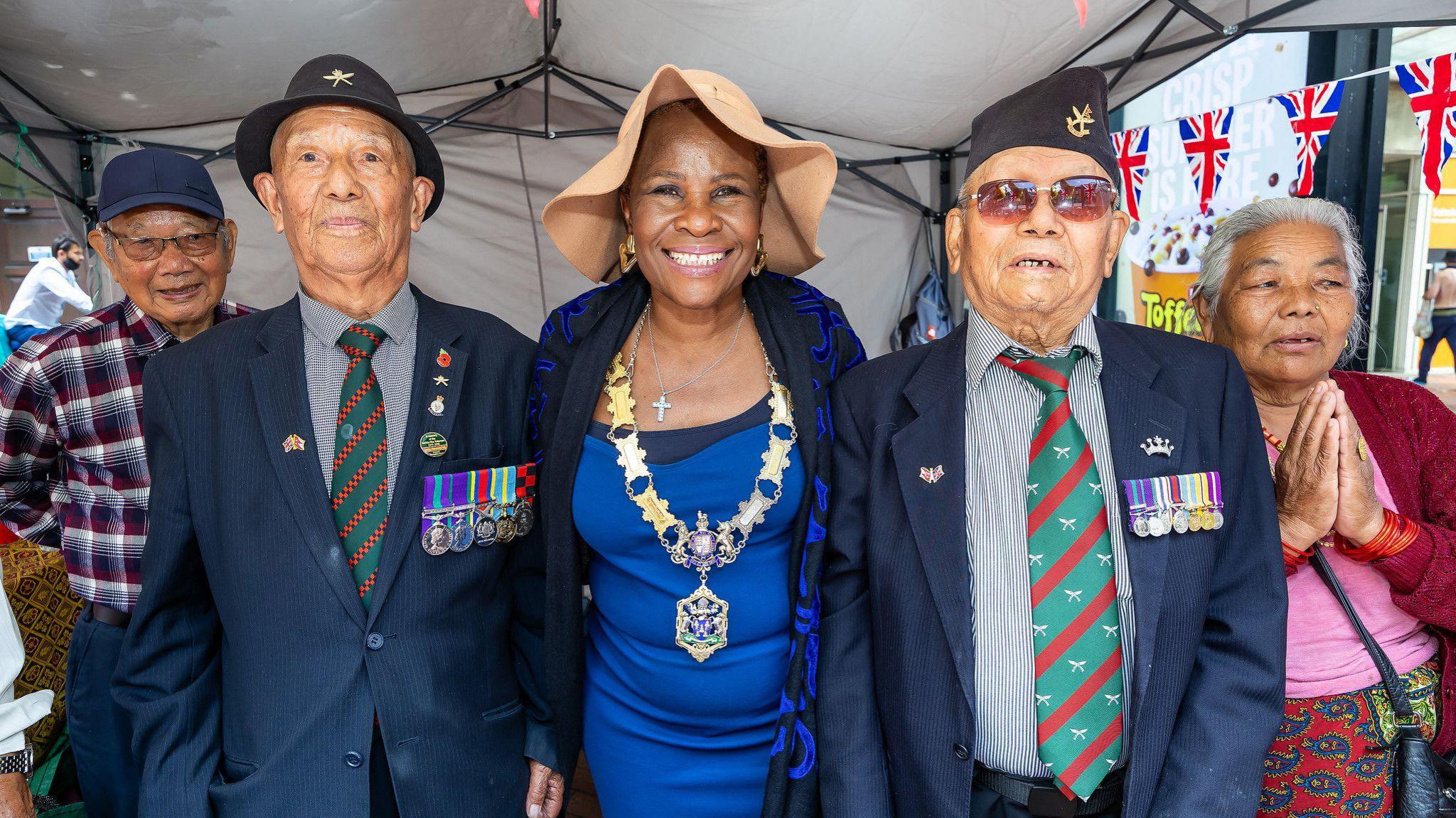 Two Gurkha veterans, wearing matching ties and medals stand next to the mayor of Reading.