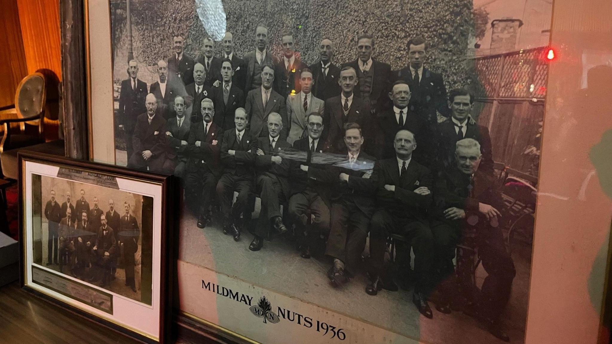 Two framed black and white photos, each of a group of suited men.