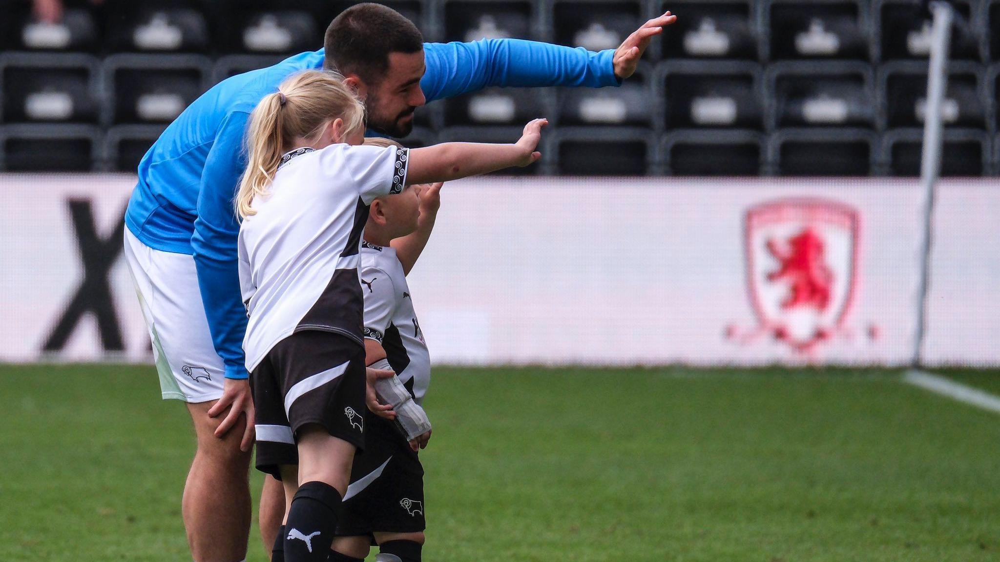 Player Eiran Cashin waving to fans with Reuben and Ivy