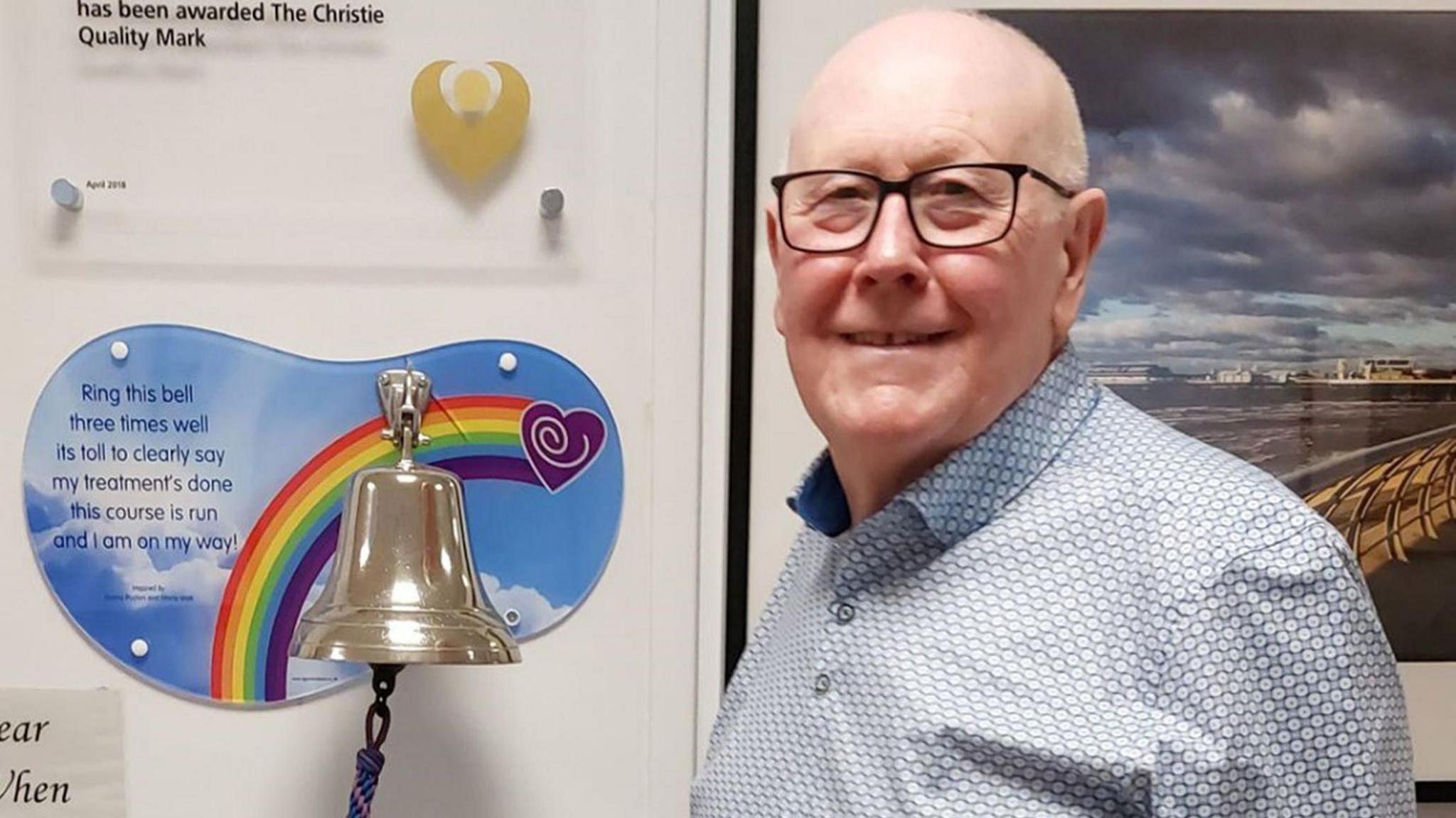 Tom Critchley poses by a bell to celebrate all-clear