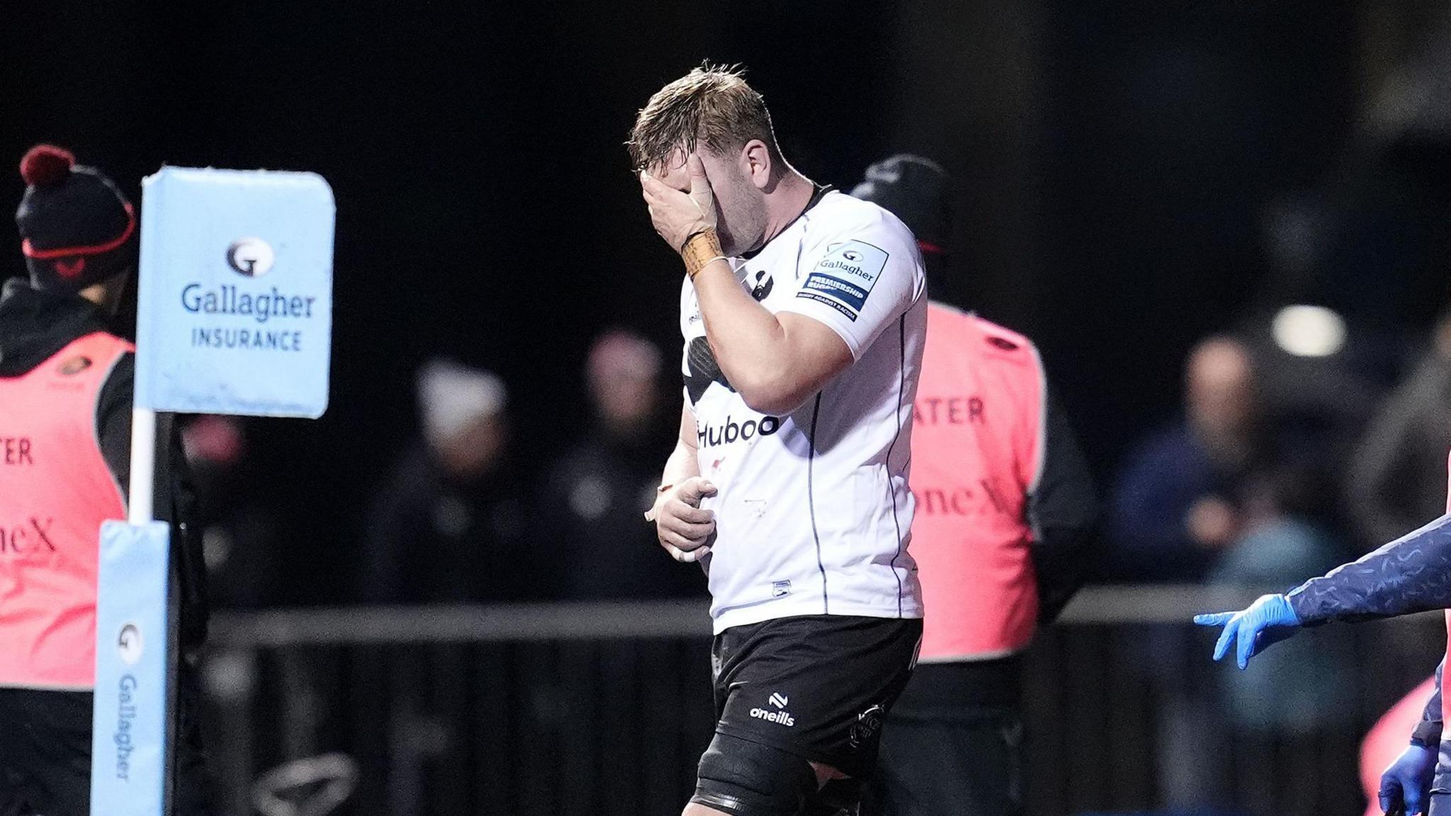 Jamie Hodgson walks off the field injured with his hand over his face