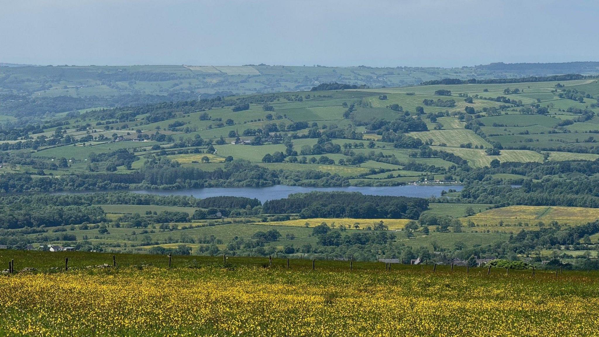 Rolling countryside with a lake in the middle distance and fields stretching into the horizon