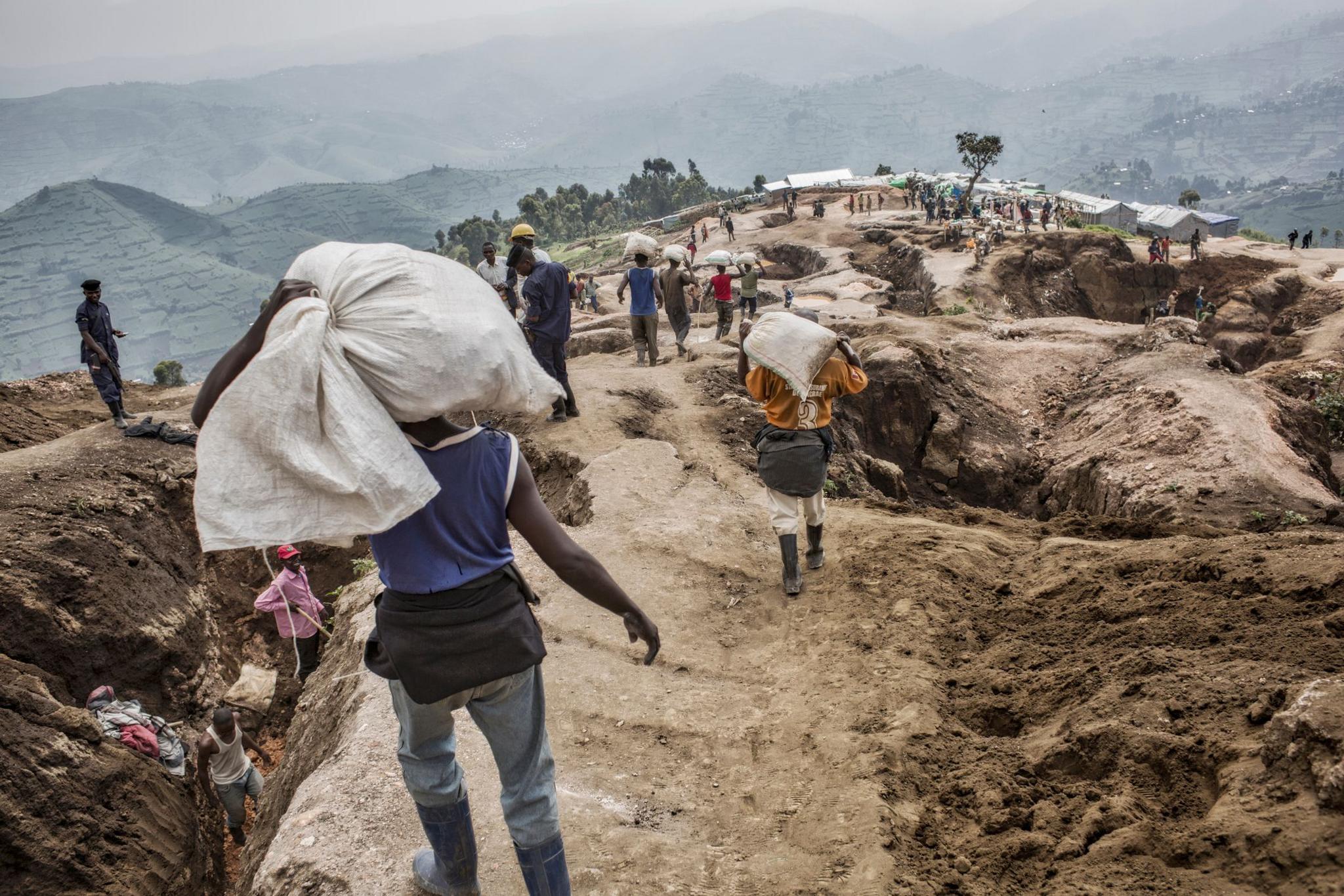 Soldiers patrol the territory around a mine where miners dig 20 metres underground. Workers can be seen carrying bags of minerals to a nearby river where they are separated from rocks and sand before being sold.