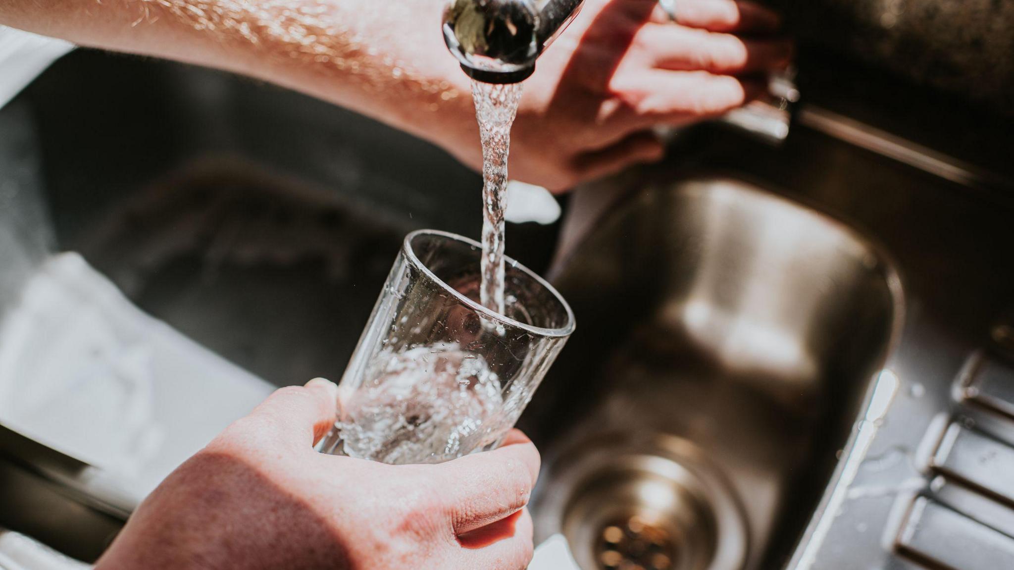 Llun rhywun yn llenwi gwydryn gyda dŵr