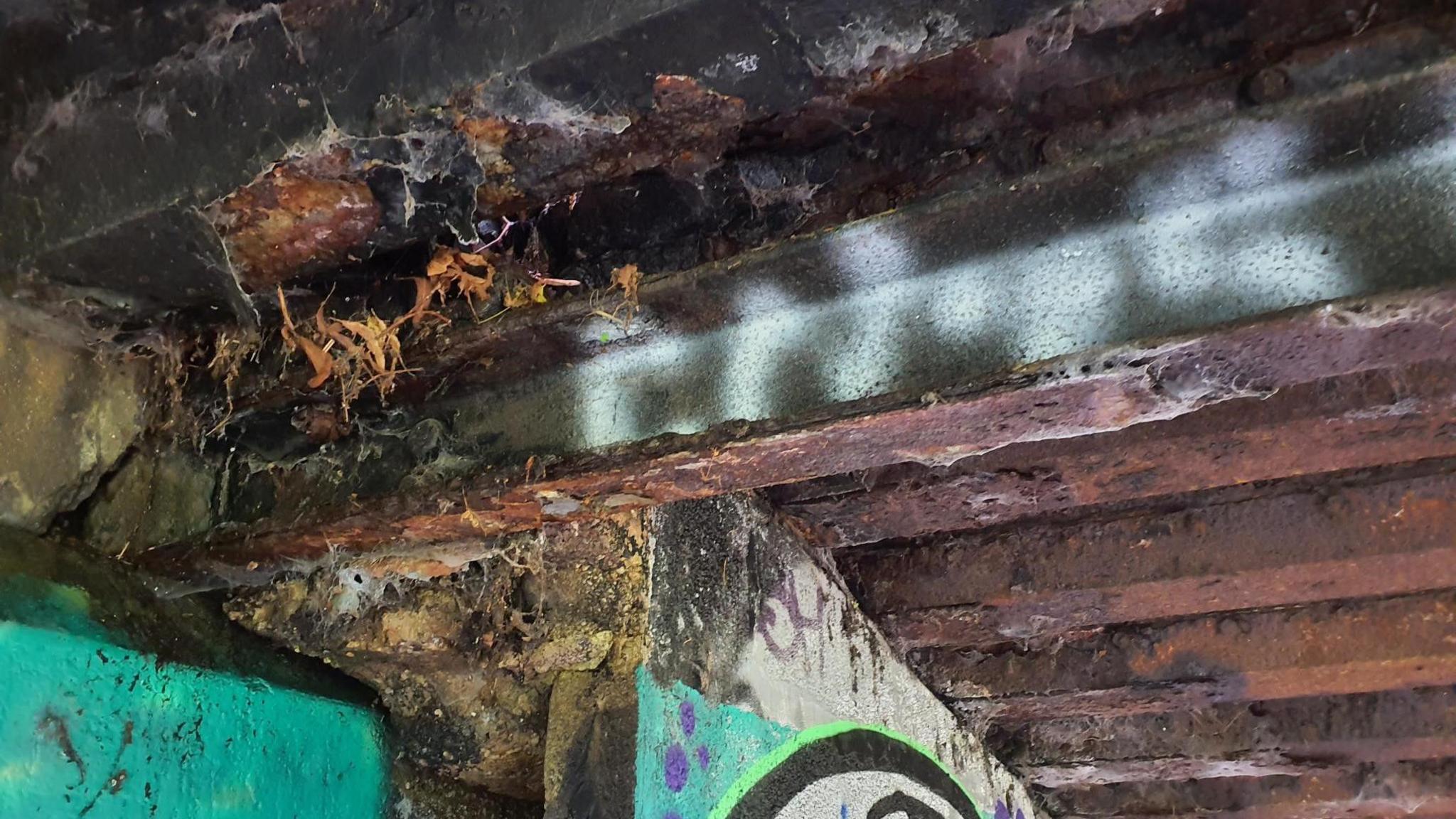 Close up of damage on Sparke Evans Park Bridge in Bristol. Graffiti can be seen underneath, as well as the foundations of the bridge. 