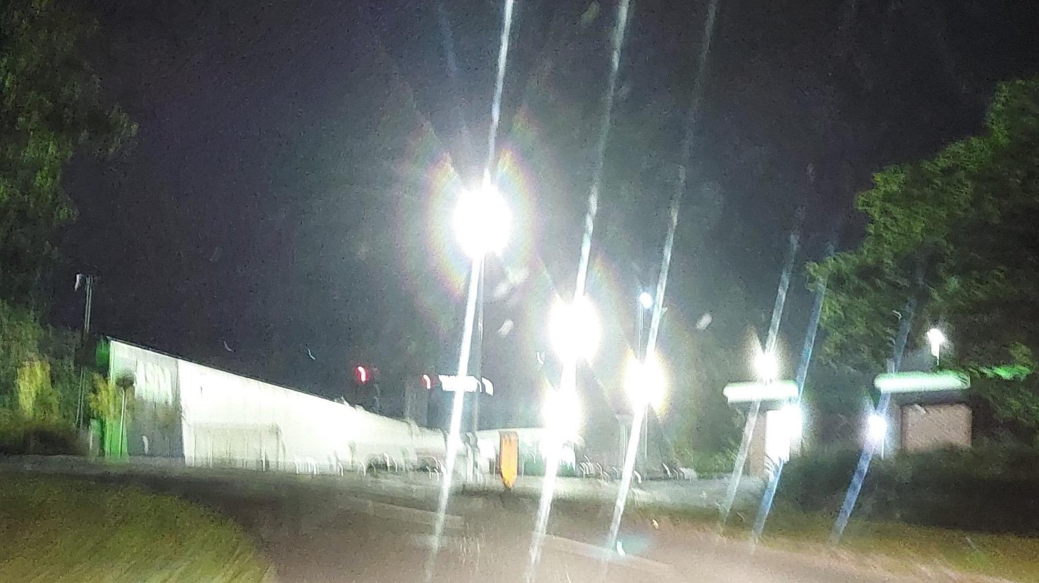 A slightly blurry photo of five bright street lights in a supermarket car park.