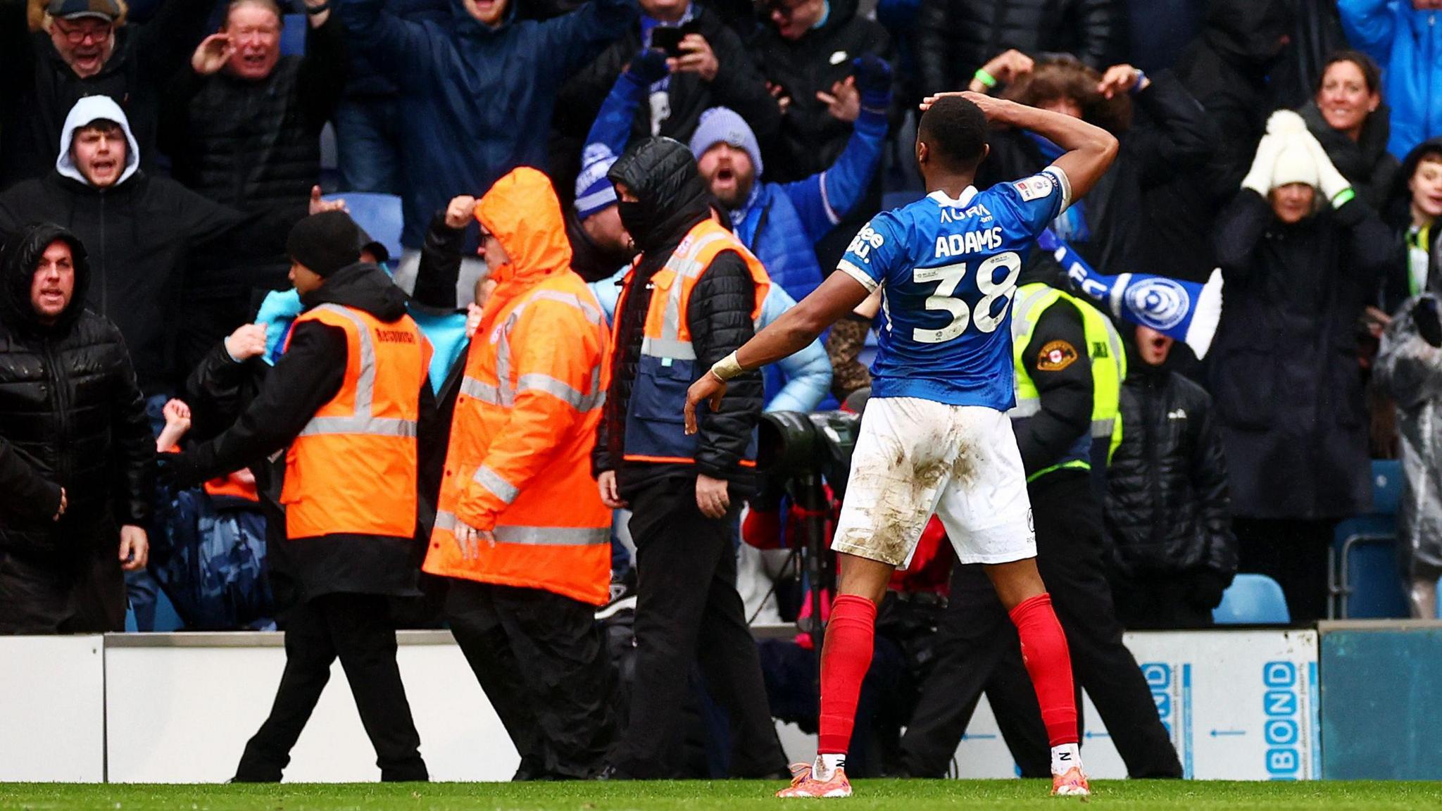 Ebou Adams celebrates in front of the Portsmouth fans after scoring 