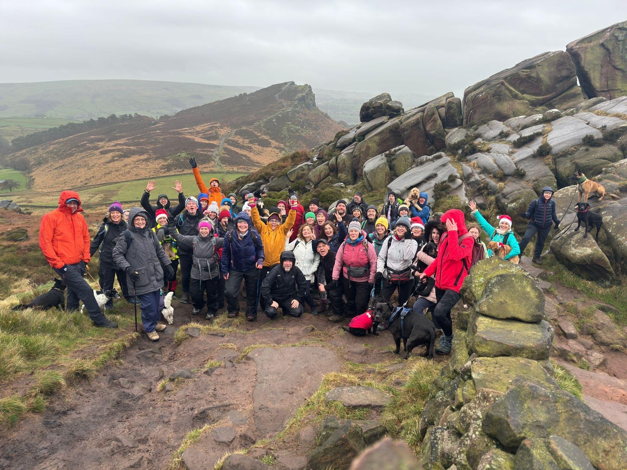 A group of walkers standing against a scenic backdrop are cheering 