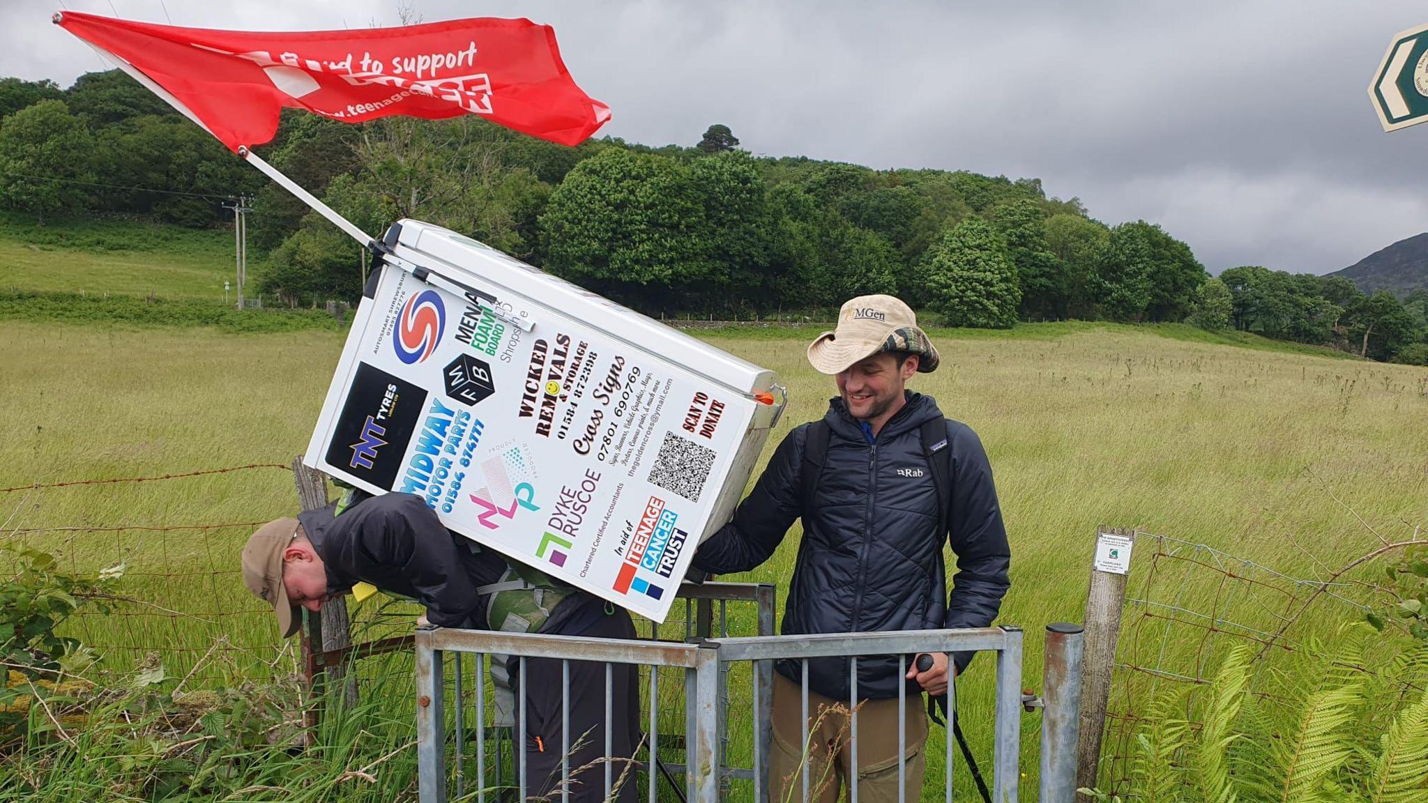 a man with a fridge on his back trying to get through a gate