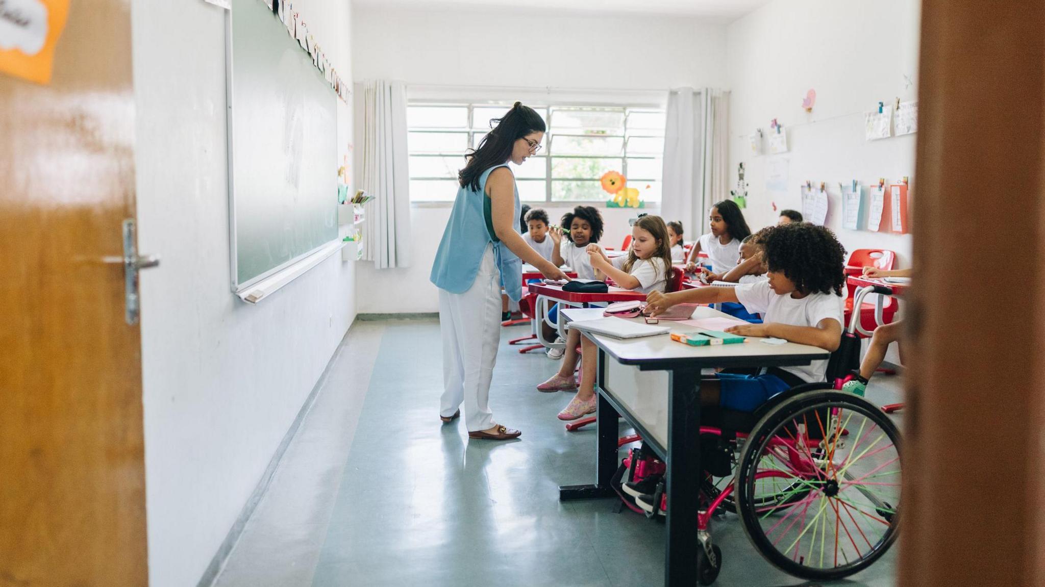 child using a wheelchair in a classroom full of non disabled children