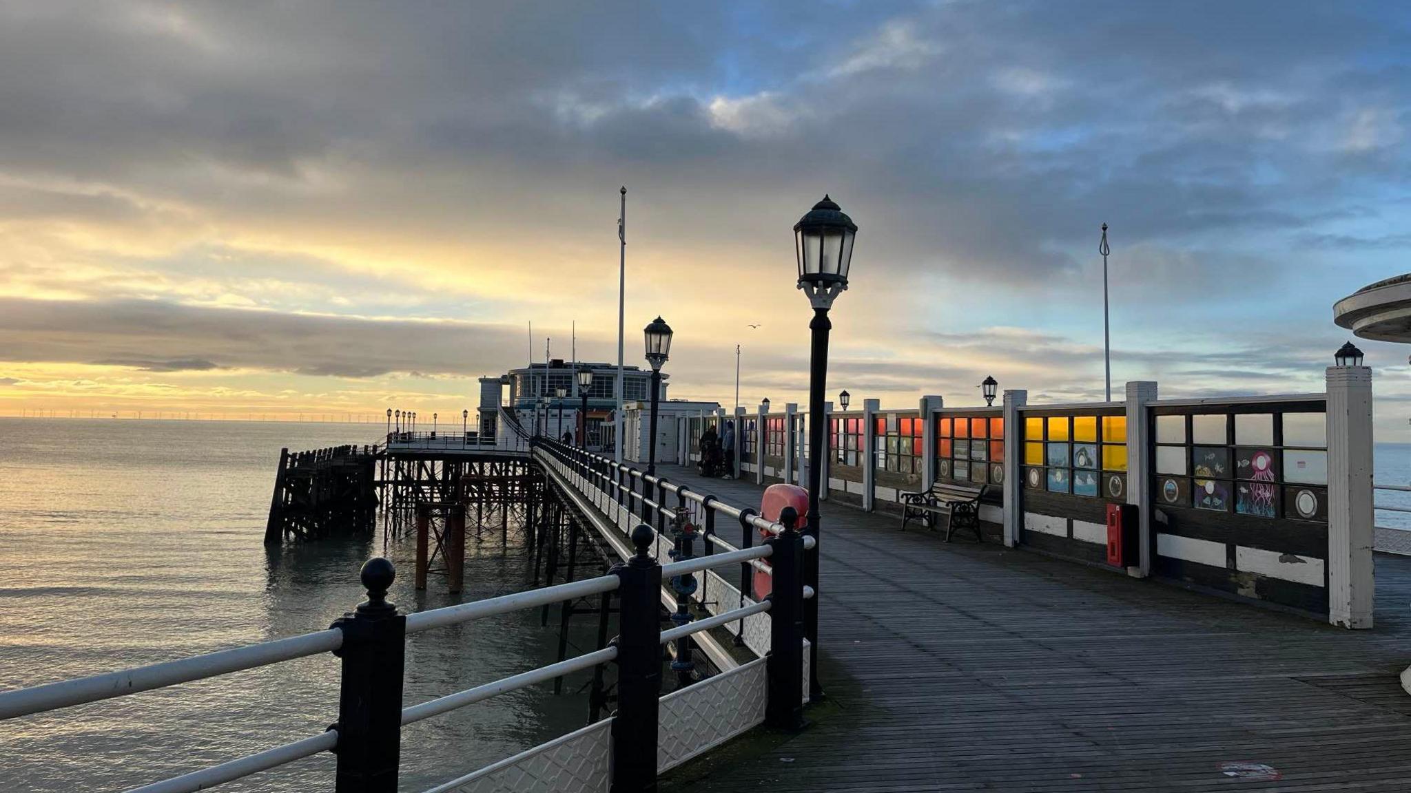 Worthing Pier with its stain glassed windows reflecting and a sunrise in the background