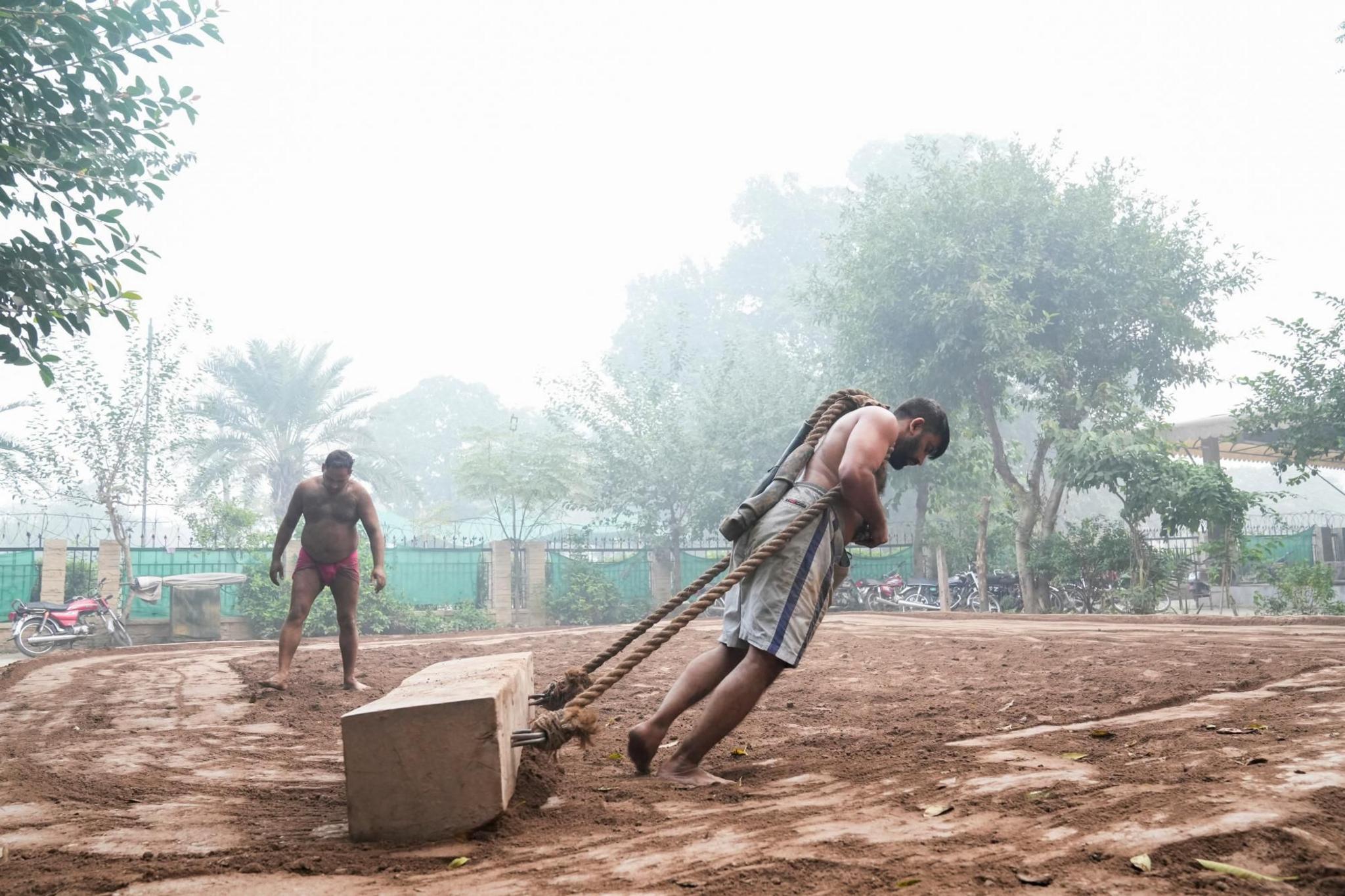 Two men pull a wooden block to level the ground at a park in Lahore, Pakistan 
