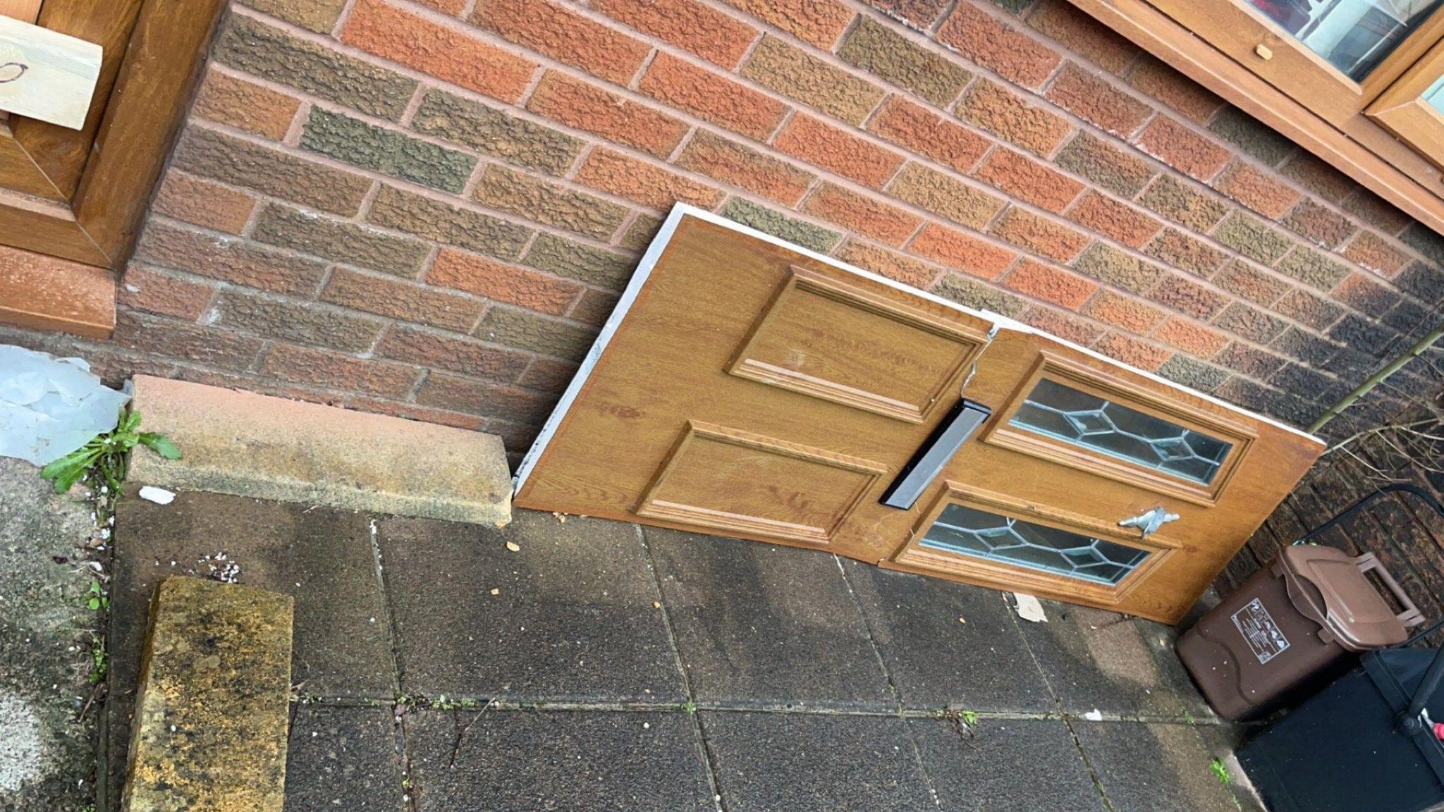 Natalie Gerrard's broken front door lies on its side outside after it was smashed in by police officers with a battering ram