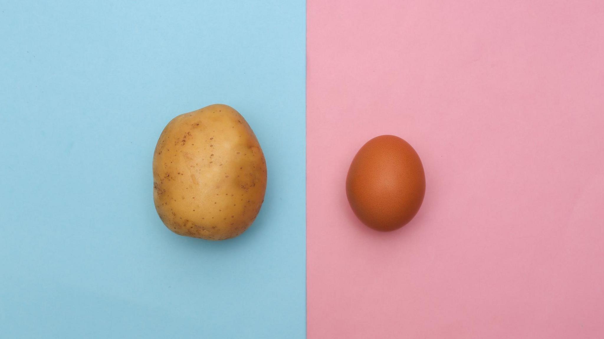 A raw potato on a blue background alongside an egg on a pink background
