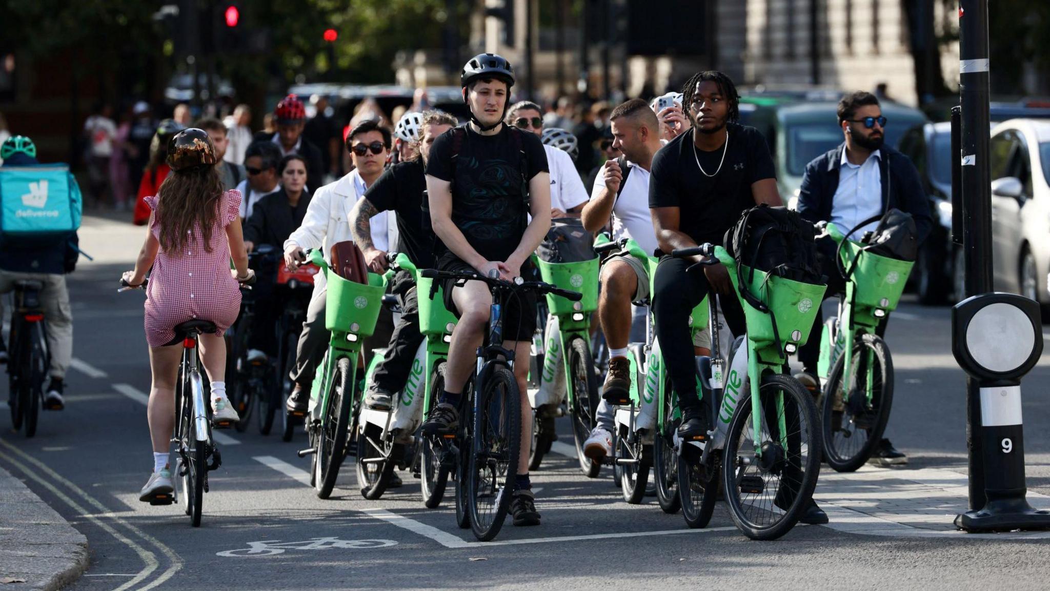 A line of cyclists waiting at traffic lights