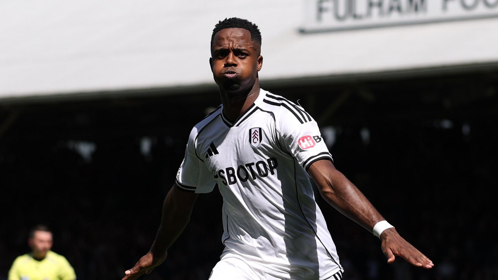 Ryan Sessegnon celebrates with arms stretched out on each side and cheeks puffed out, wearing Fulham's white kit