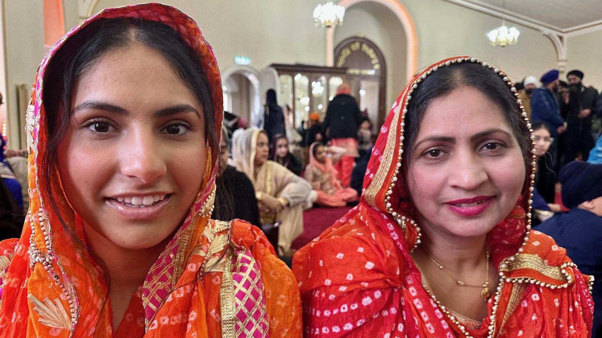 Harmanpreet  and her mother ae wearing bright orange saris.