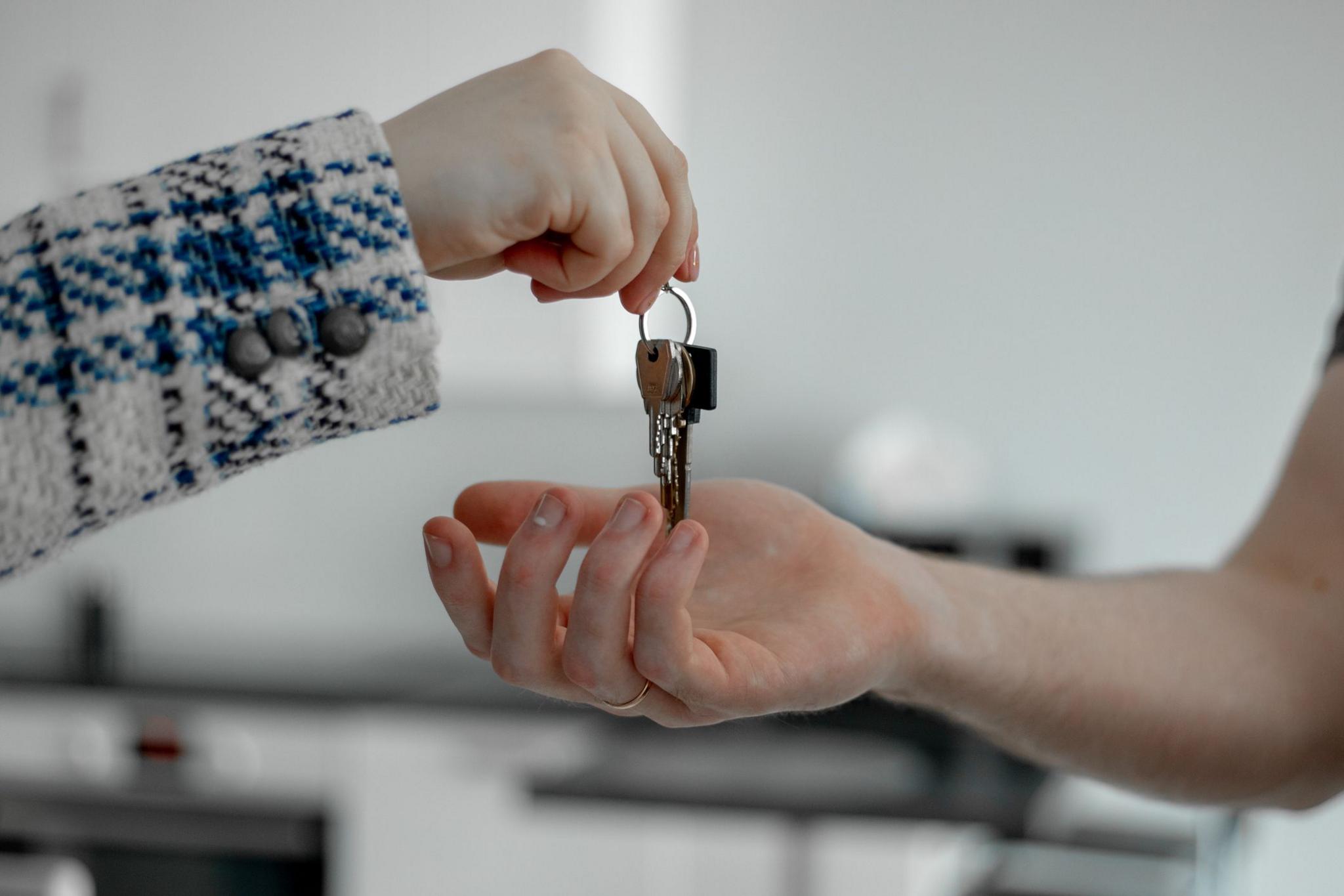 One hand gives house keys to another hand 