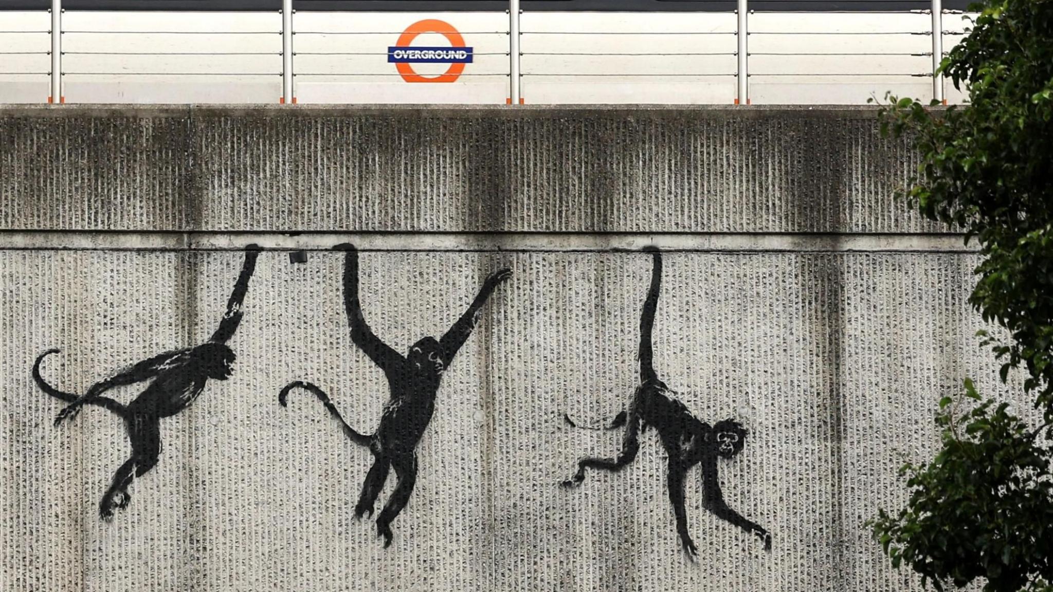 A painting on a bridge of three monkeys swinging