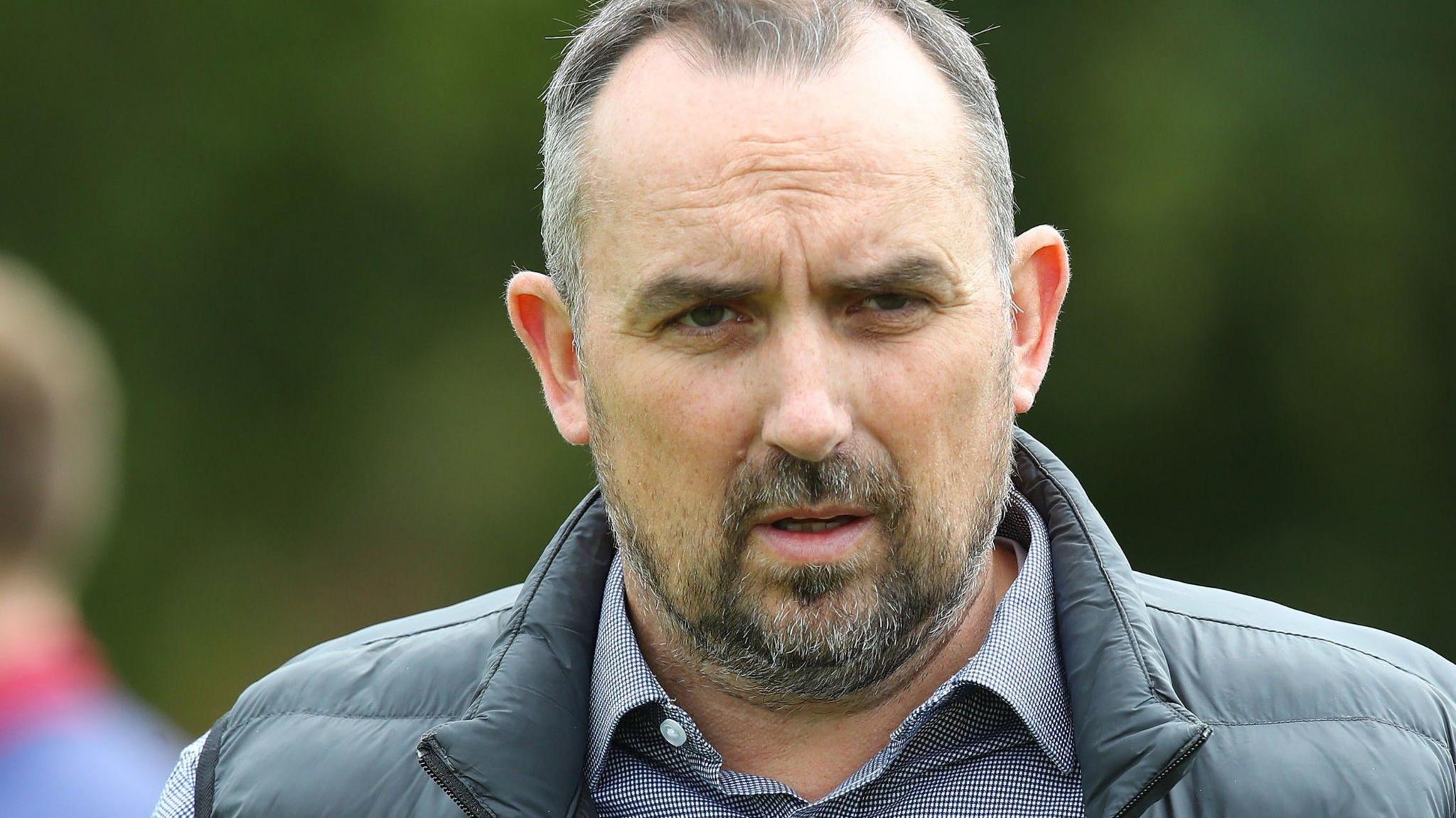 Northampton Town chairman Kelvin Thomas in a blue chequered shirt with a buttoned collar and a black gilet.