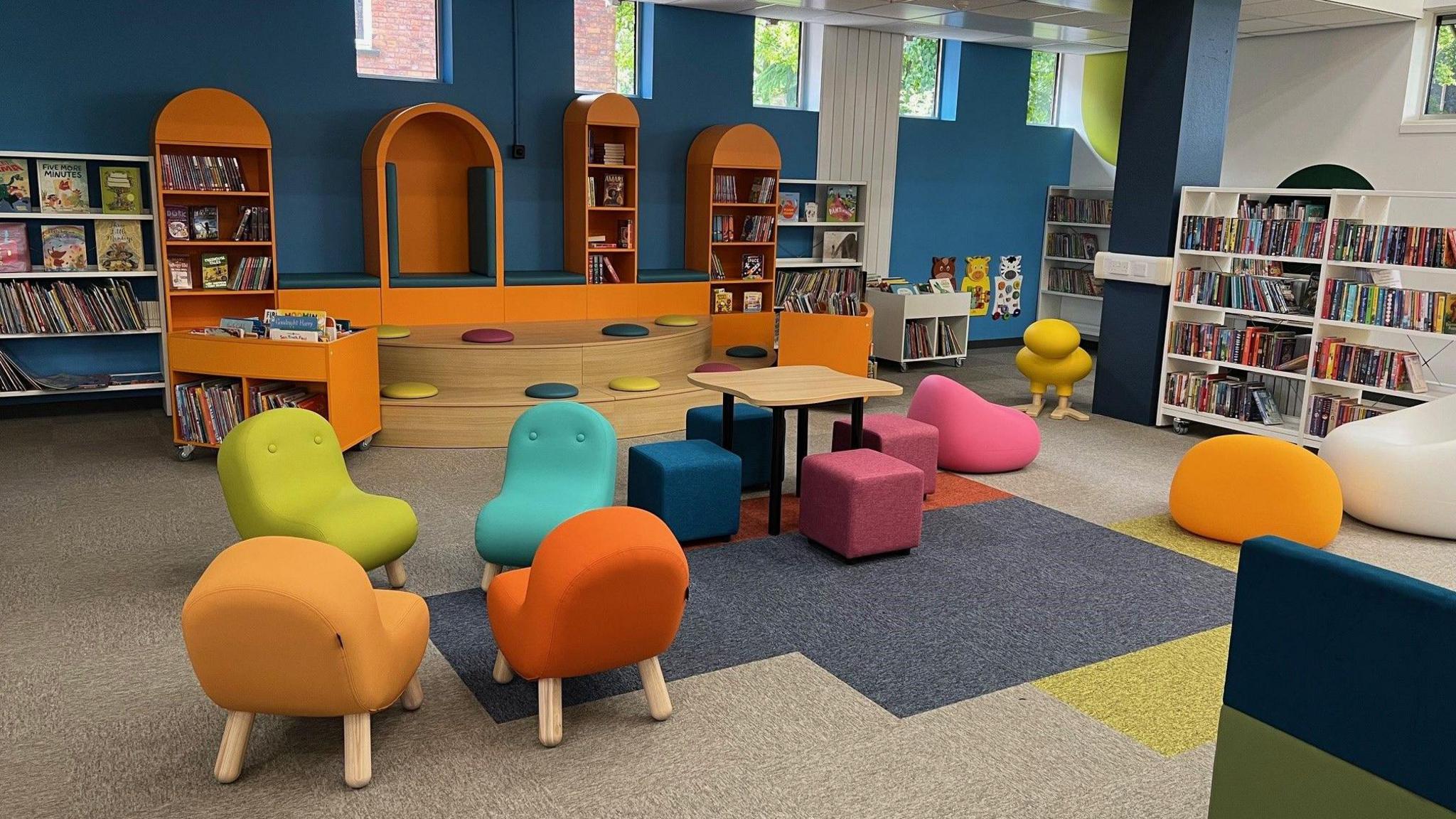 A children's section of a library with brightly coloured seating and book shelves.