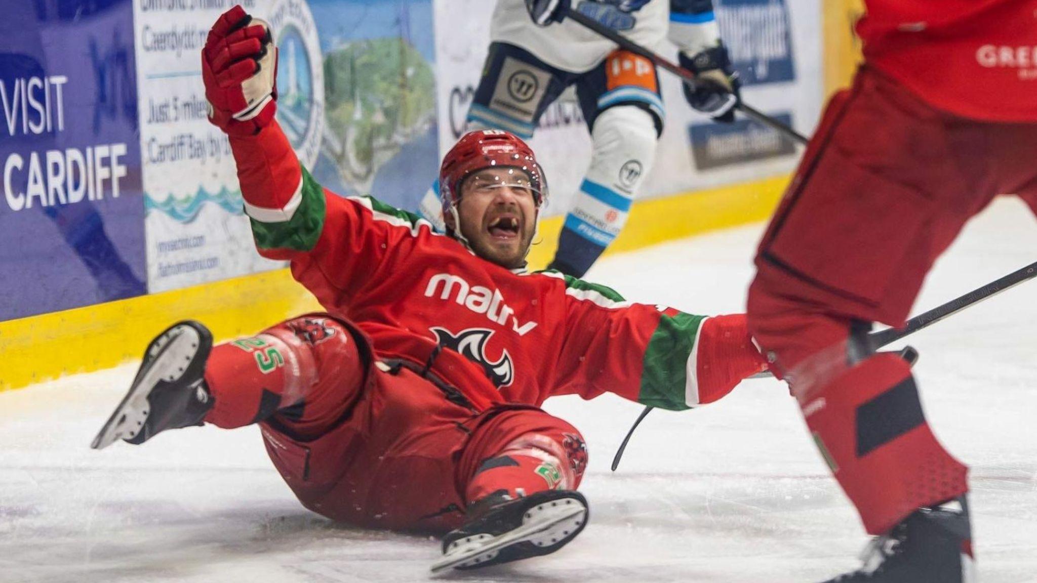 Cardiff Devils Riley Brandt on his back on the ice grinning celebrates with arms spread wide