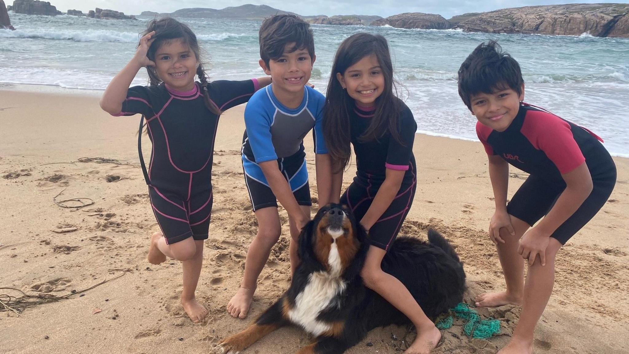 Mali the dog lying on a sandy beach with Sarah Recinos Ralda's four children 