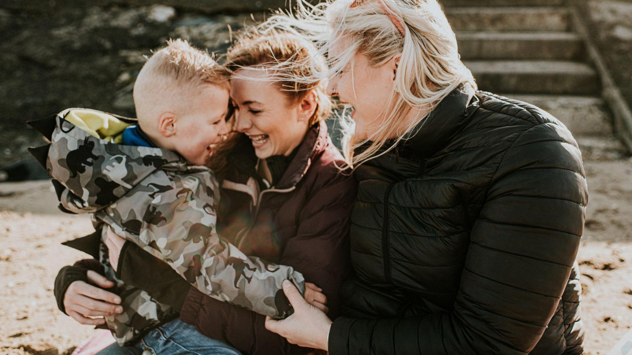 Stock photo of two women and a child laughing on the beach