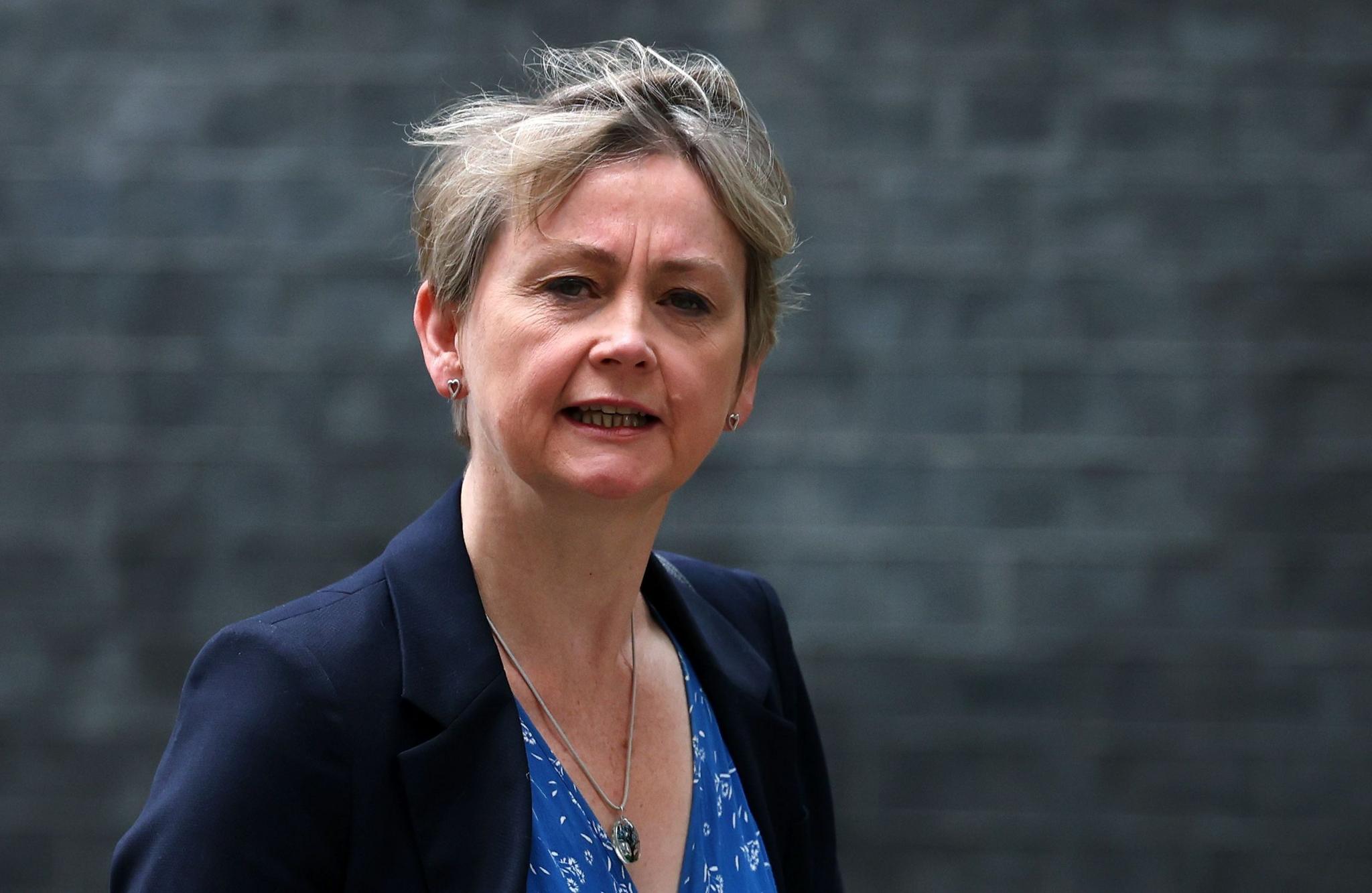 Home Secretary Yvette Cooper looking at the camera. She has short blonde hair and is wearing a light blue top, necklace with a pendant and a navy blazer.