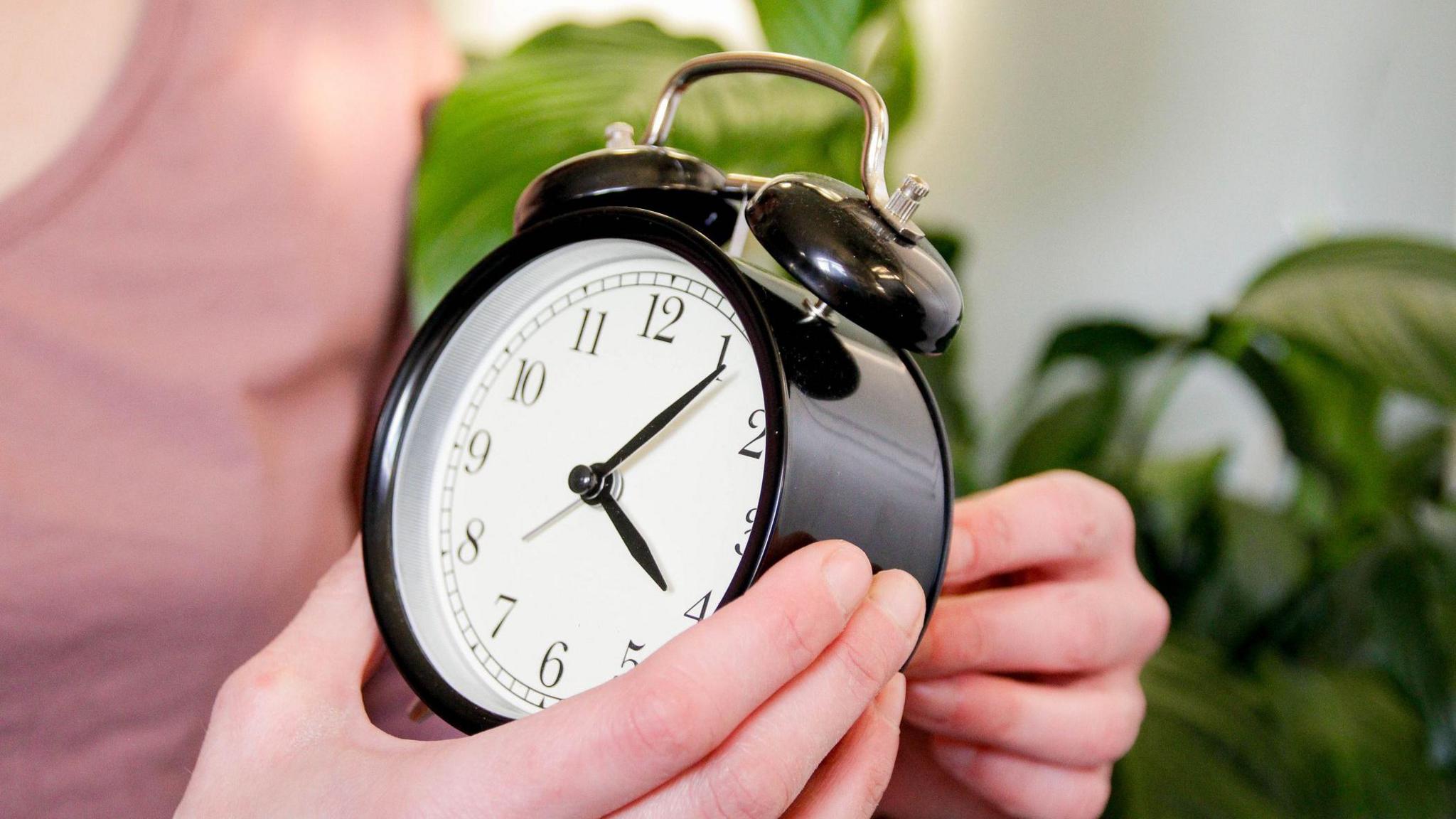 Close-up of someone setting the time on an analogue clock