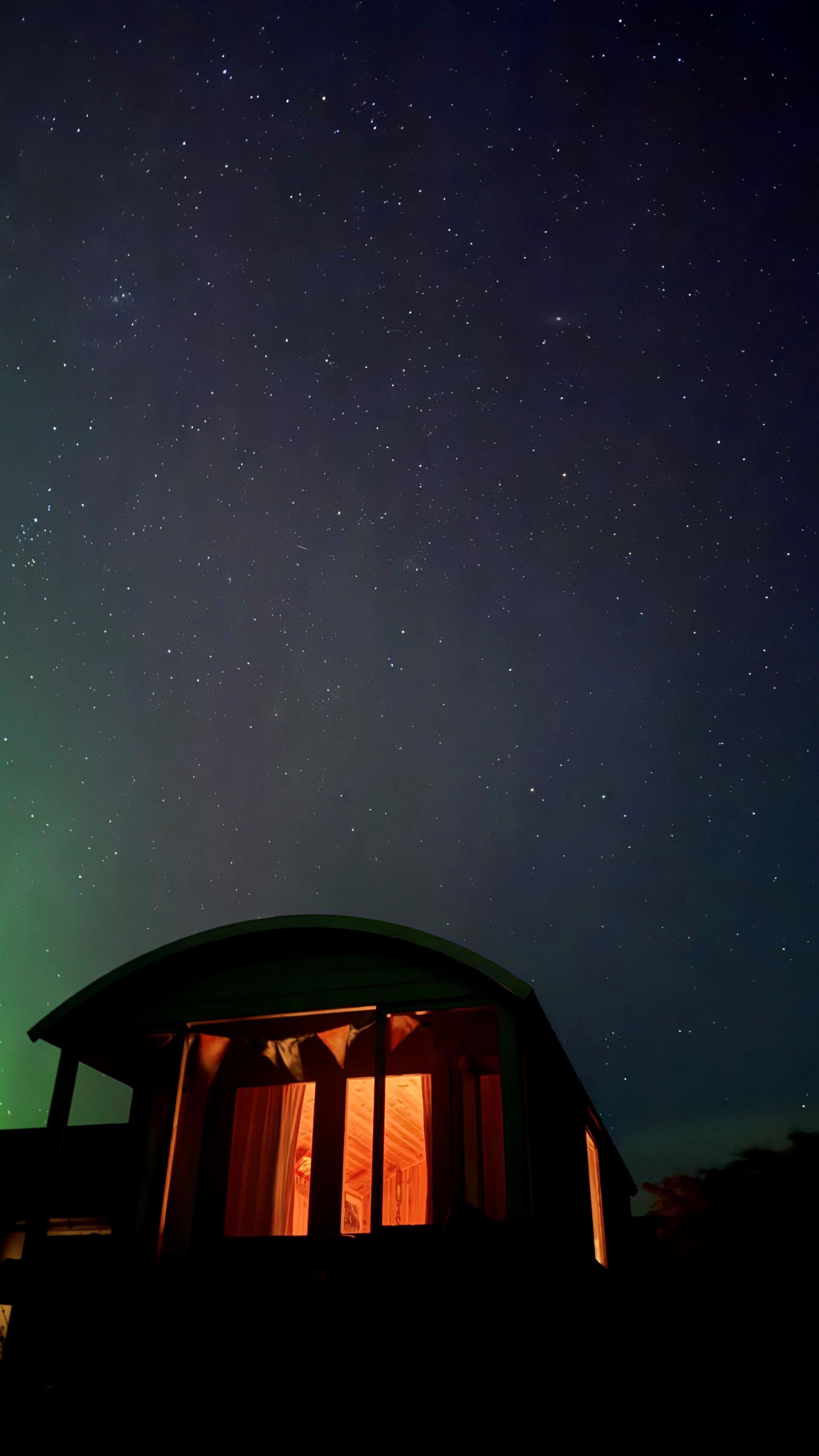 An illuminated building makes a nice silhouette against a starry night sky with a green light.
