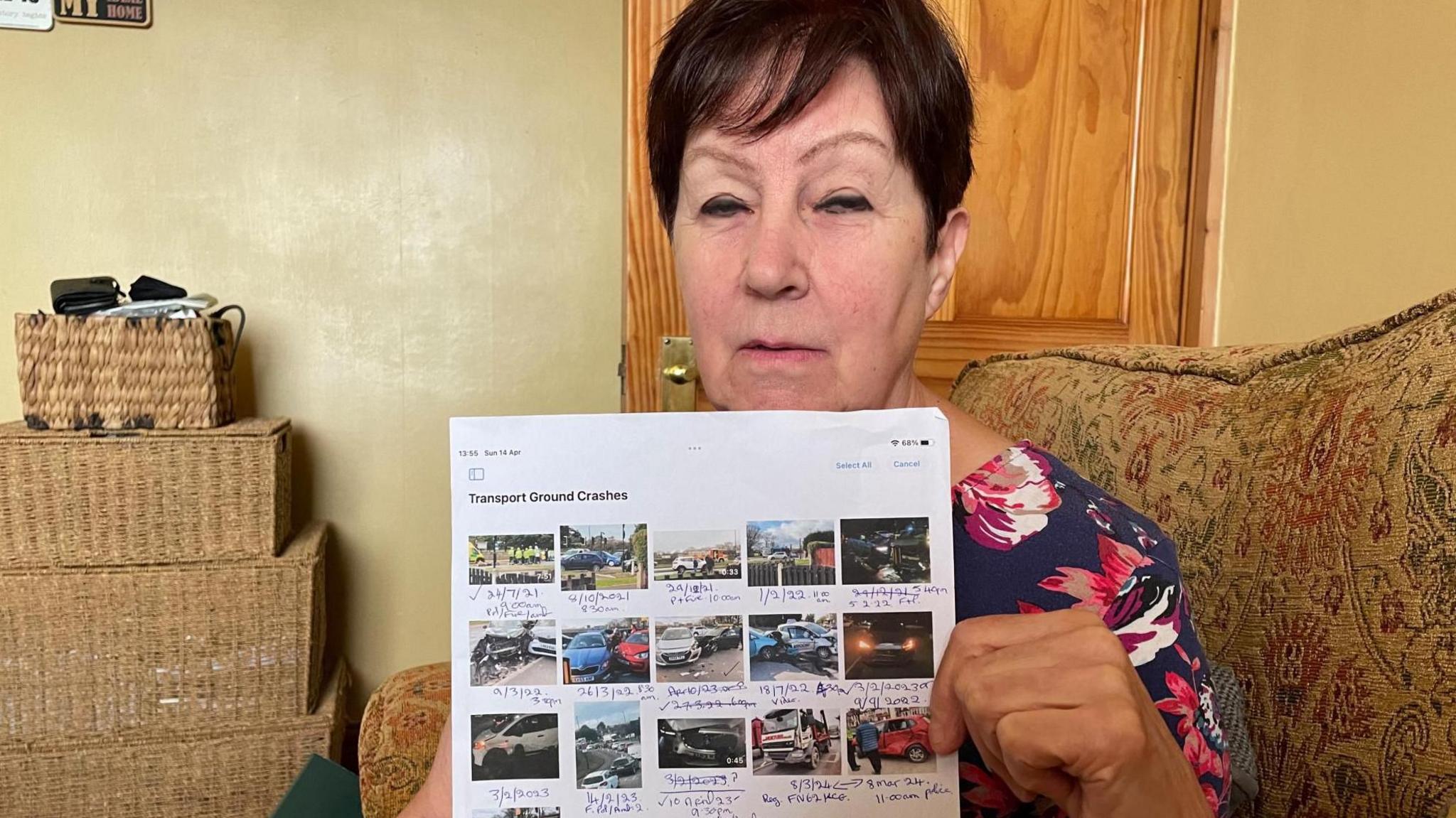 A woman holding a piece of paper showing several photos of car crashes.