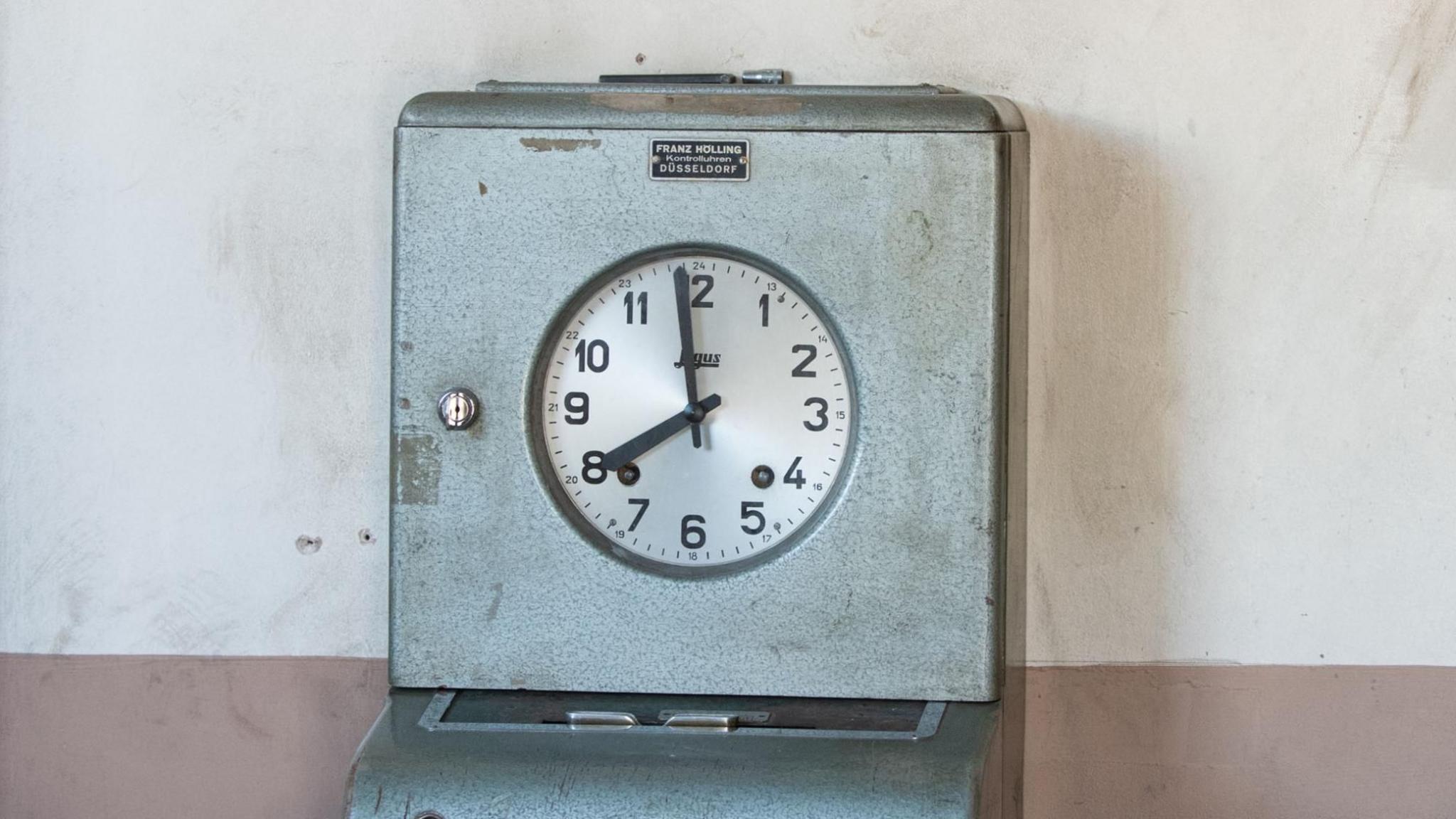 A factory clocking-on/off machine - showing a clockface enclosed in a grey metal box