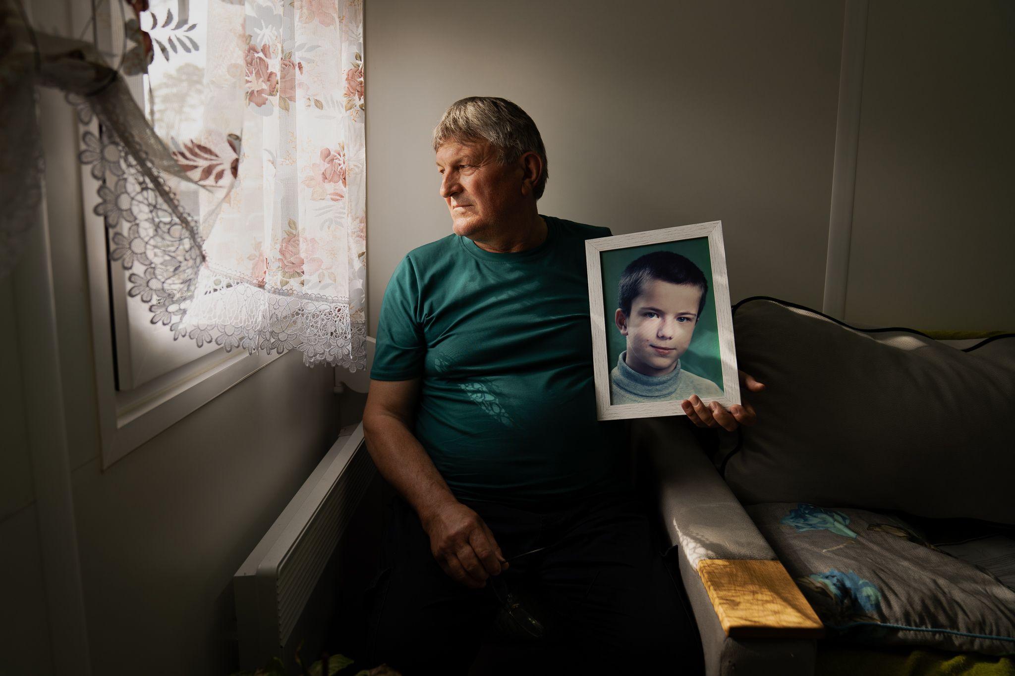 Petro Sereda holding a framed picture of his son Artem.