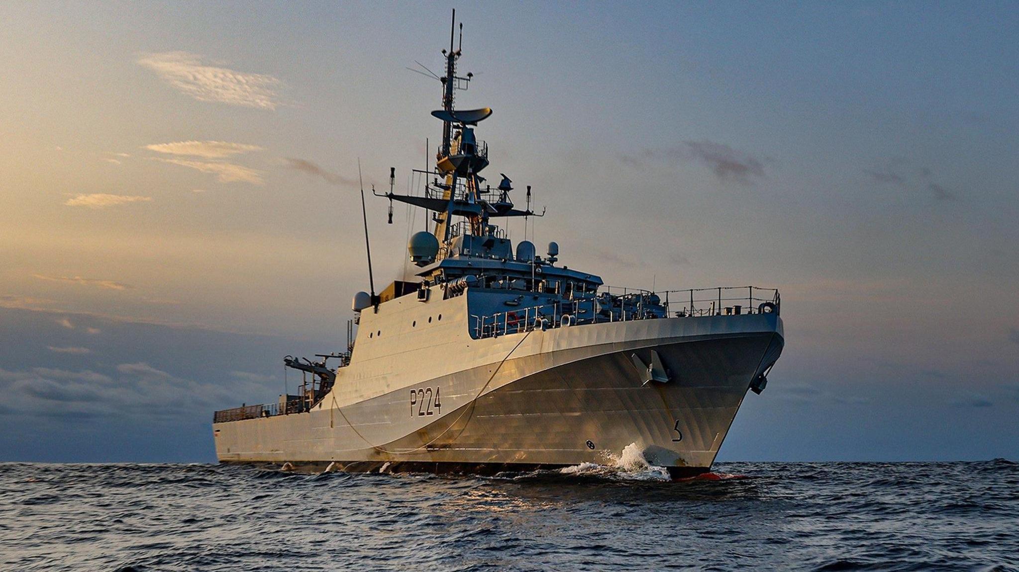 HMS Trent, seen in a calm sea in golden sunlight