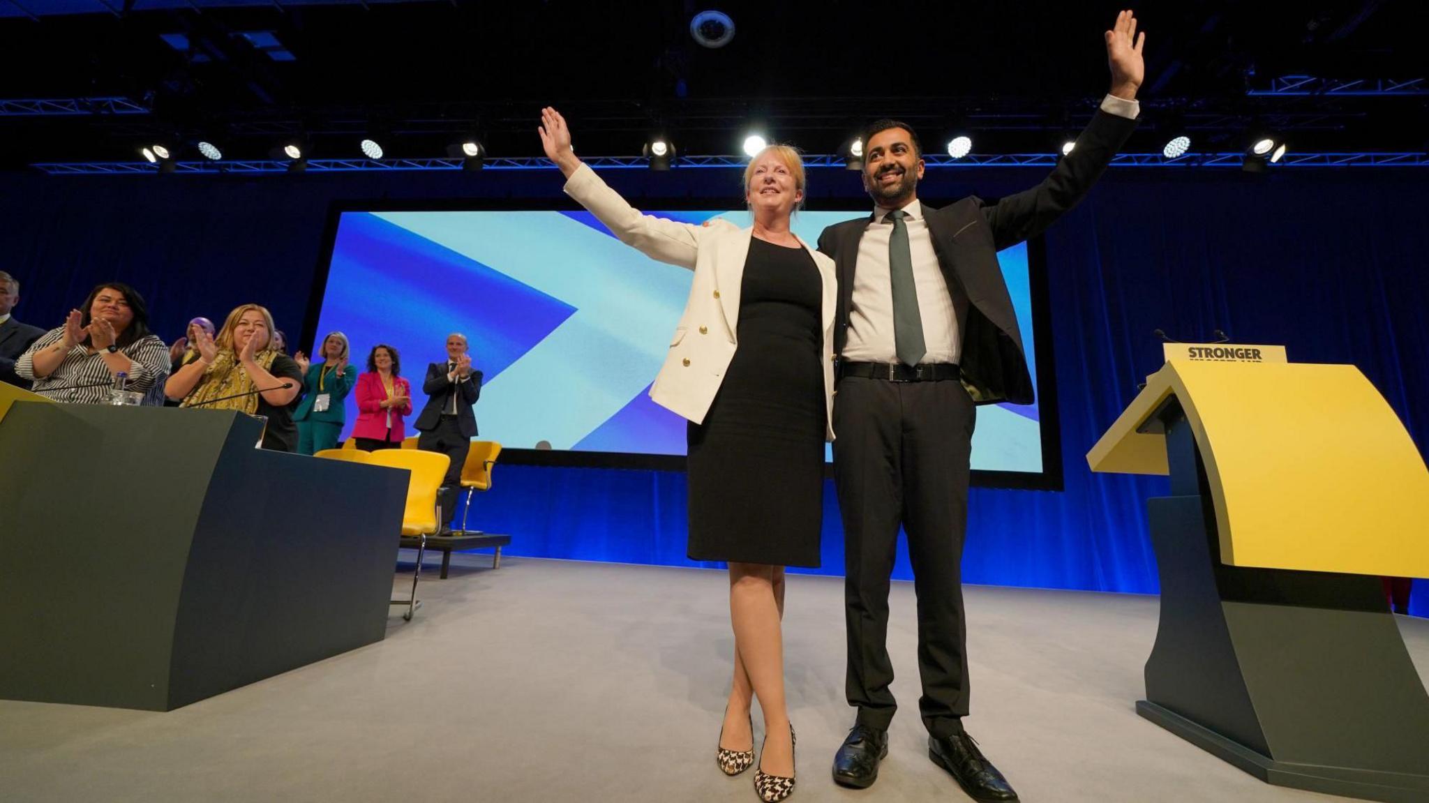 Shona Robison and Humza Yousaf waving to delegates at the 2023 SNP conference