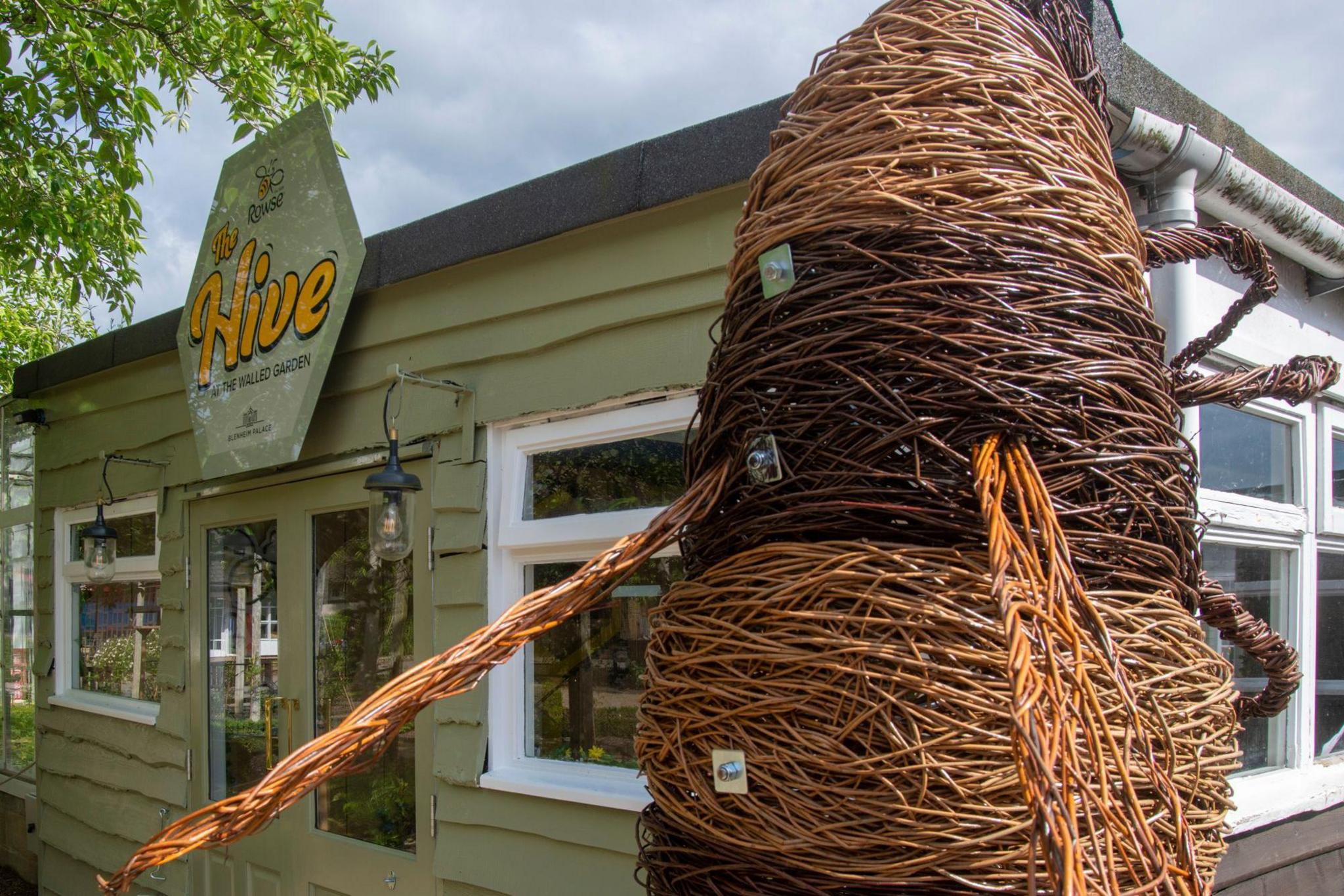 The entrance to the bee experience, with a giant statue of a bee made out of wicker